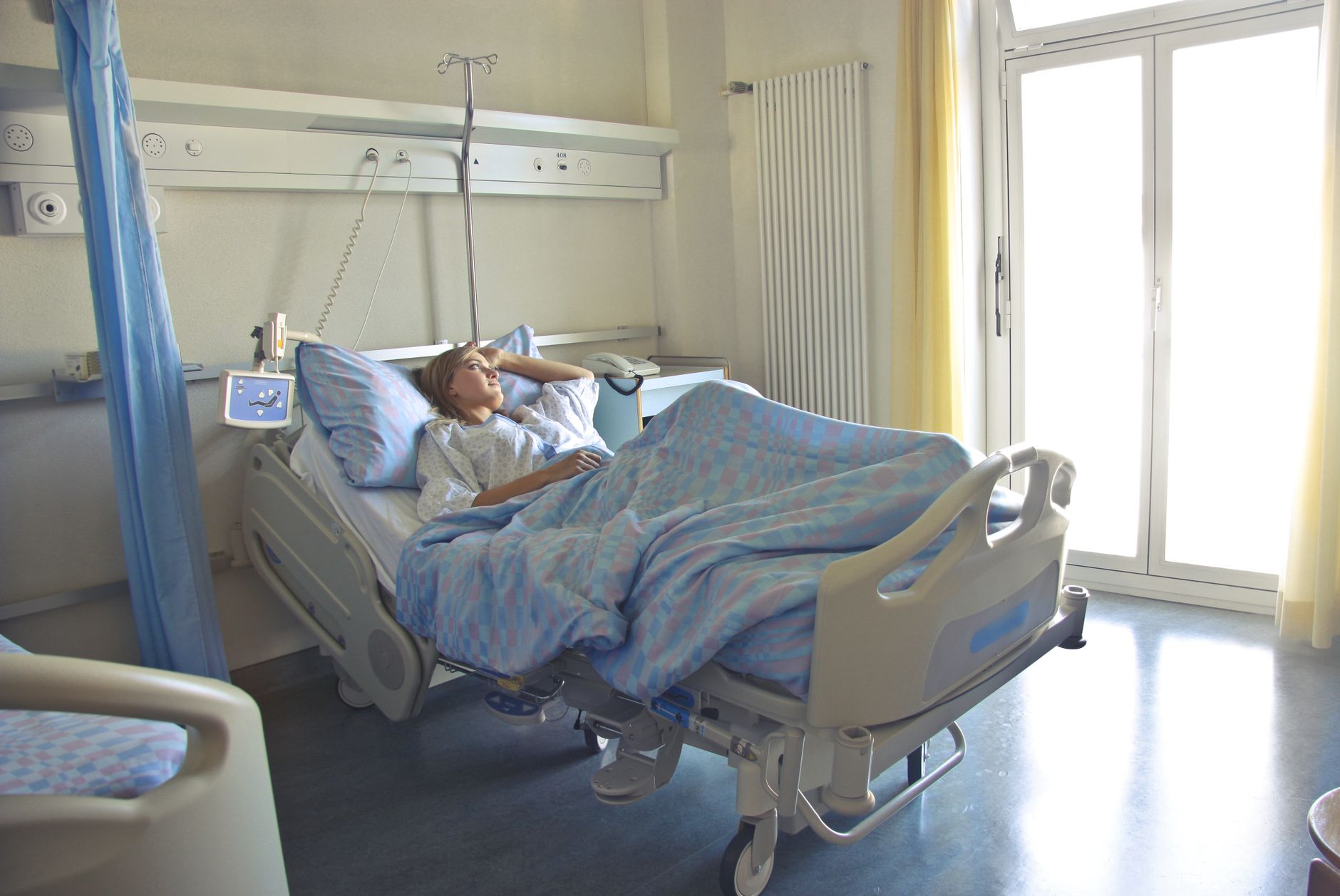 A calm pregnant woman lying on a hospital bed with a fetal monitor attached, soft natural light from a window