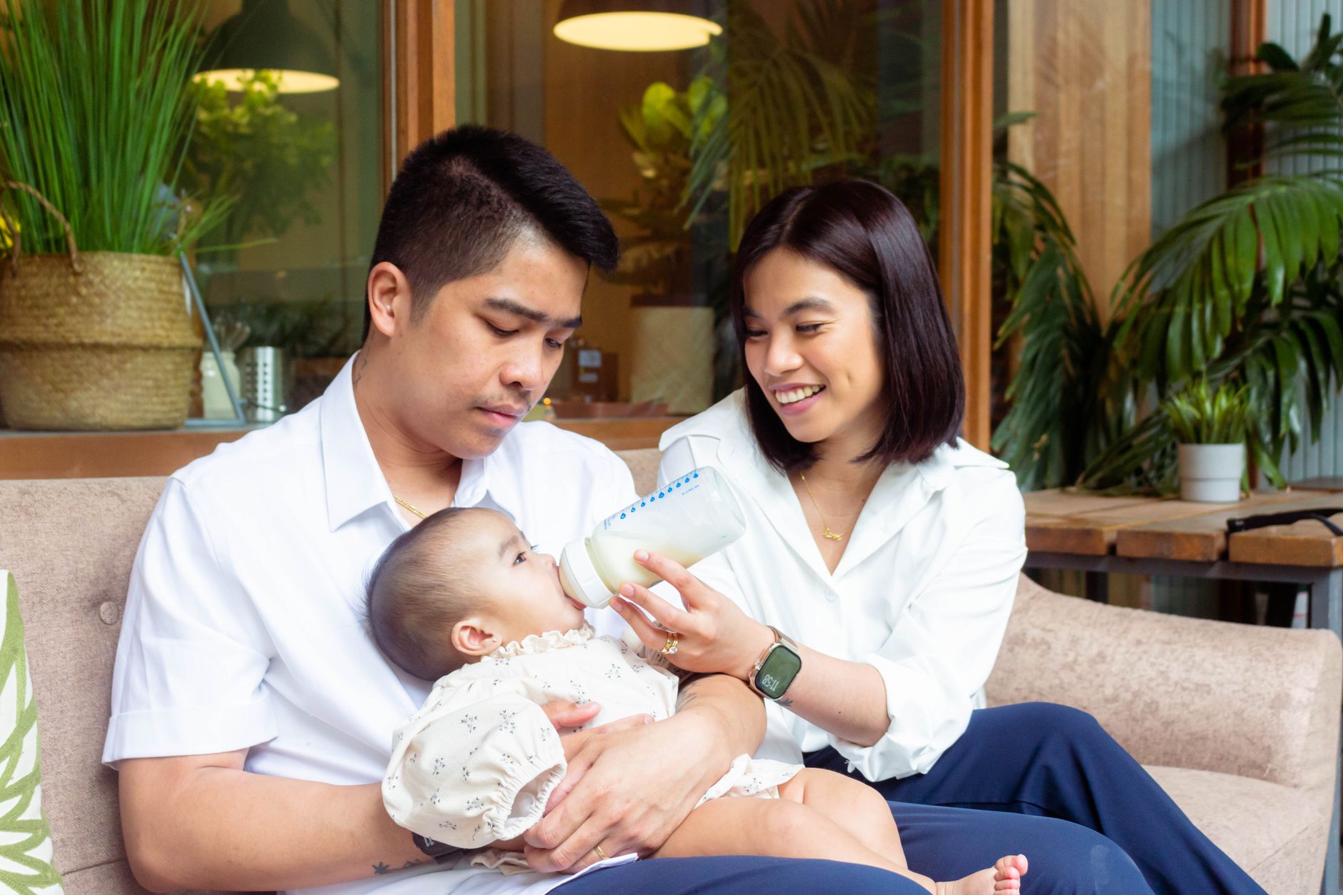 A father gently holding and feeding a baby a bottle, showing active participation in childcare.