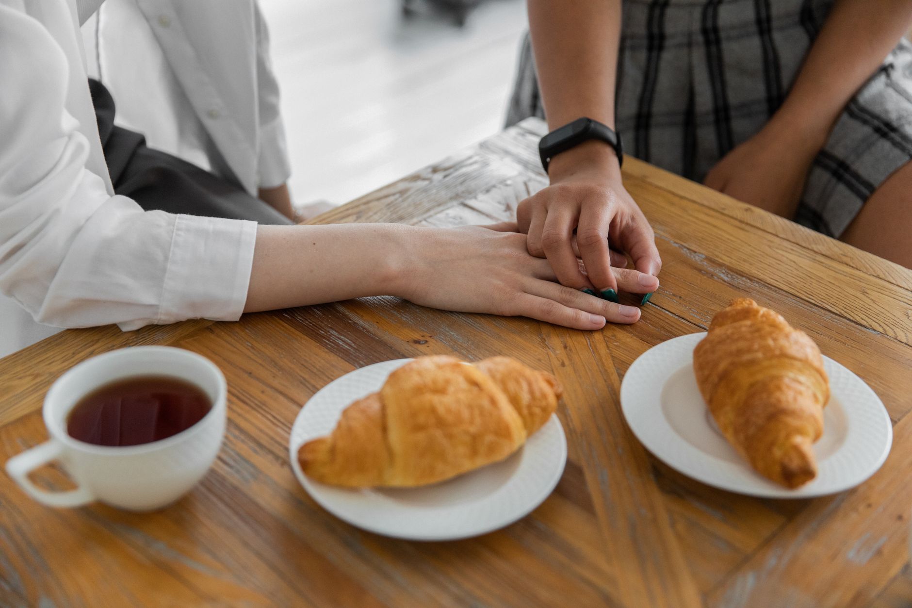 Couple sitting at a kitchen table reviewing a pregnancy test result together, smiling and holding a cup of tea, soft natural light
