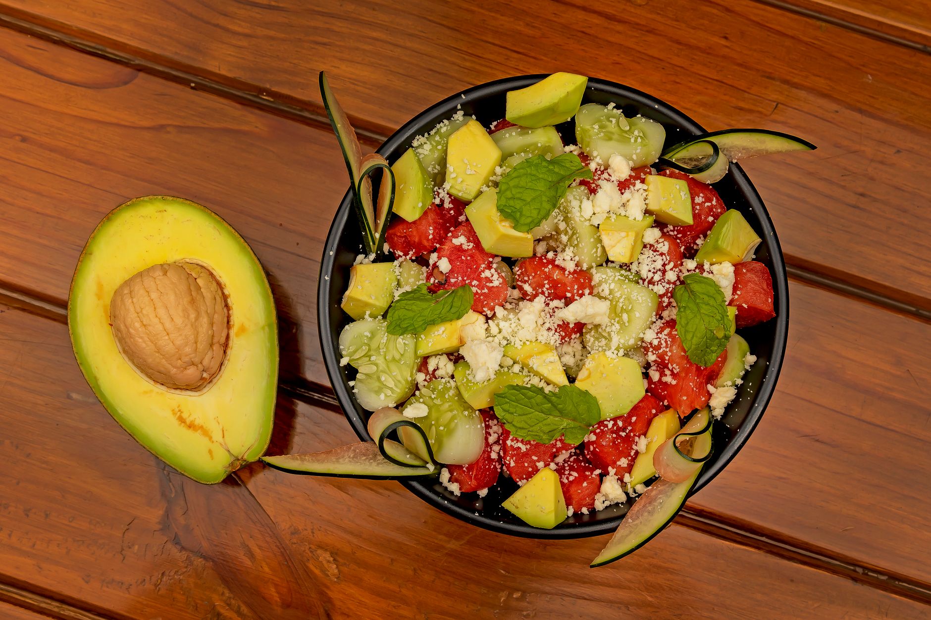 A colorful bowl of fresh spinach, avocado slices, and watermelon cubes, showcasing natural electrolyte-rich foods for pregnant women
