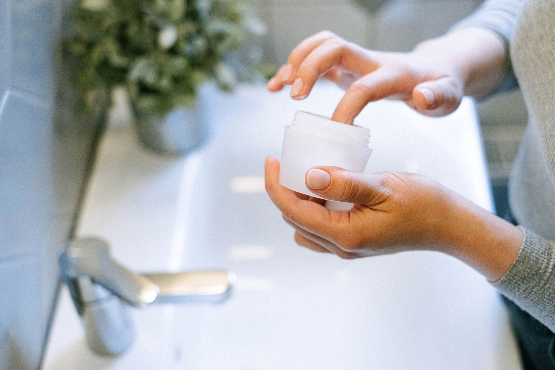 A gentle morning routine with a pregnant woman applying a thin layer of self‑tanner in front of a bathroom mirror, emphasizing safe application technique