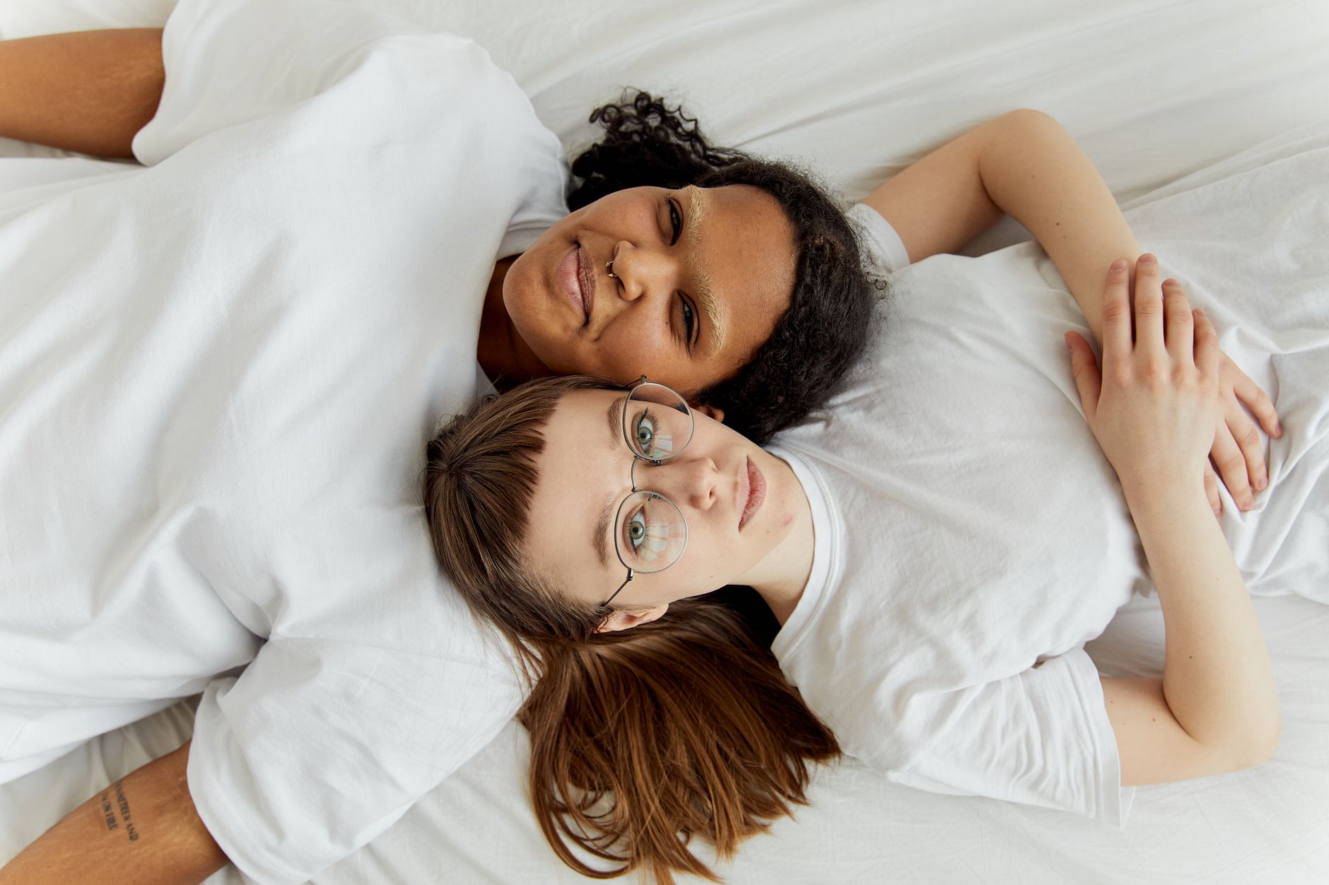 A cozy bedroom with a crib in the corner, a couple sitting on the edge of the bed with a baby monitor on the nightstand