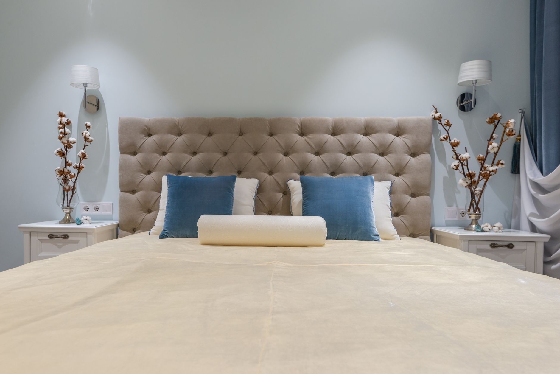 A tidy bedroom with blackout curtains, a comfortable bed, and a white noise machine