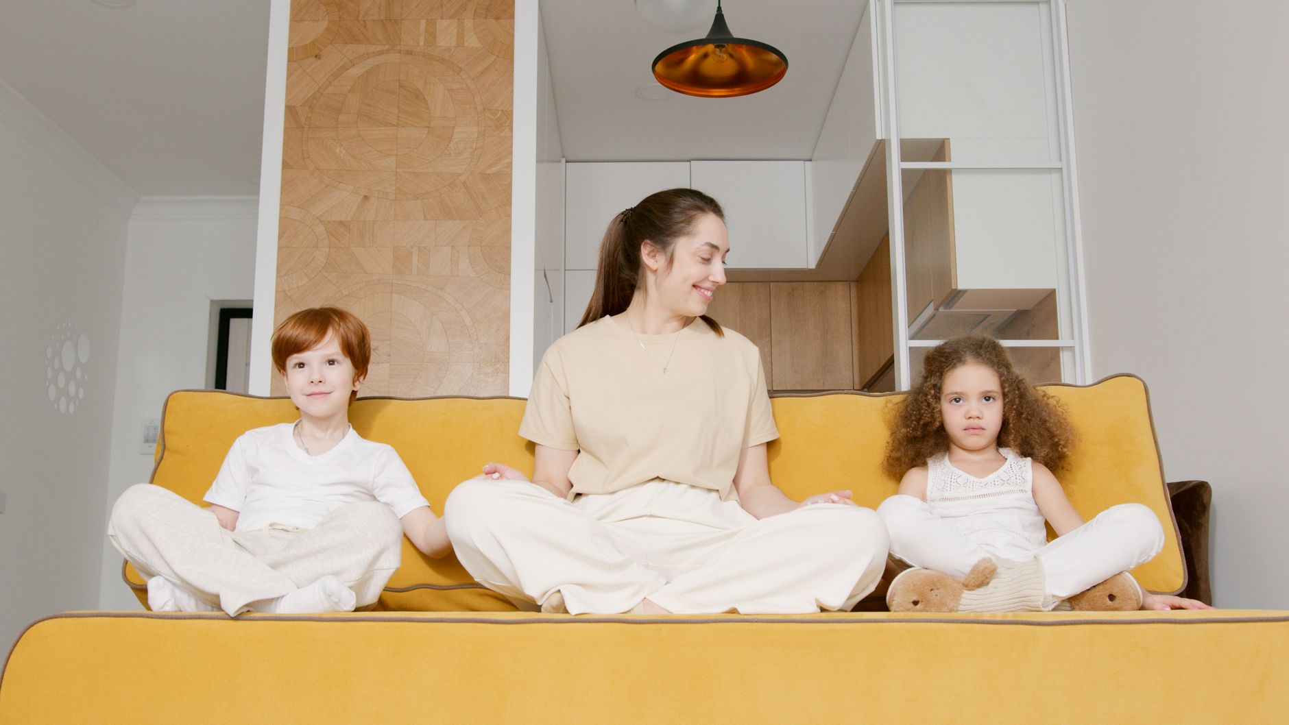 A mom sitting on a couch with her two kids, looking relieved and happy
