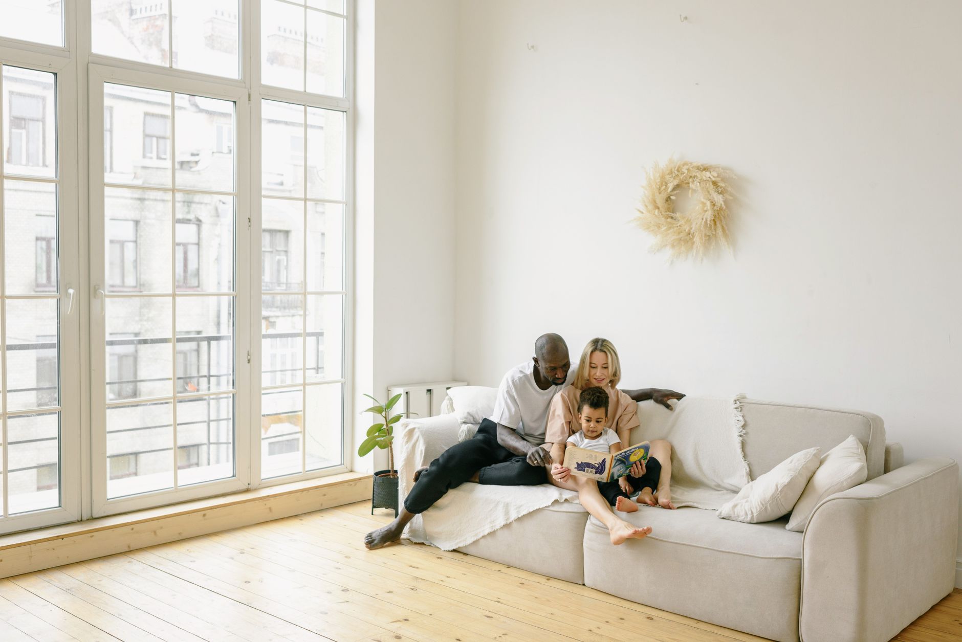 A family sitting on a couch reading a book together, with a cozy home background.