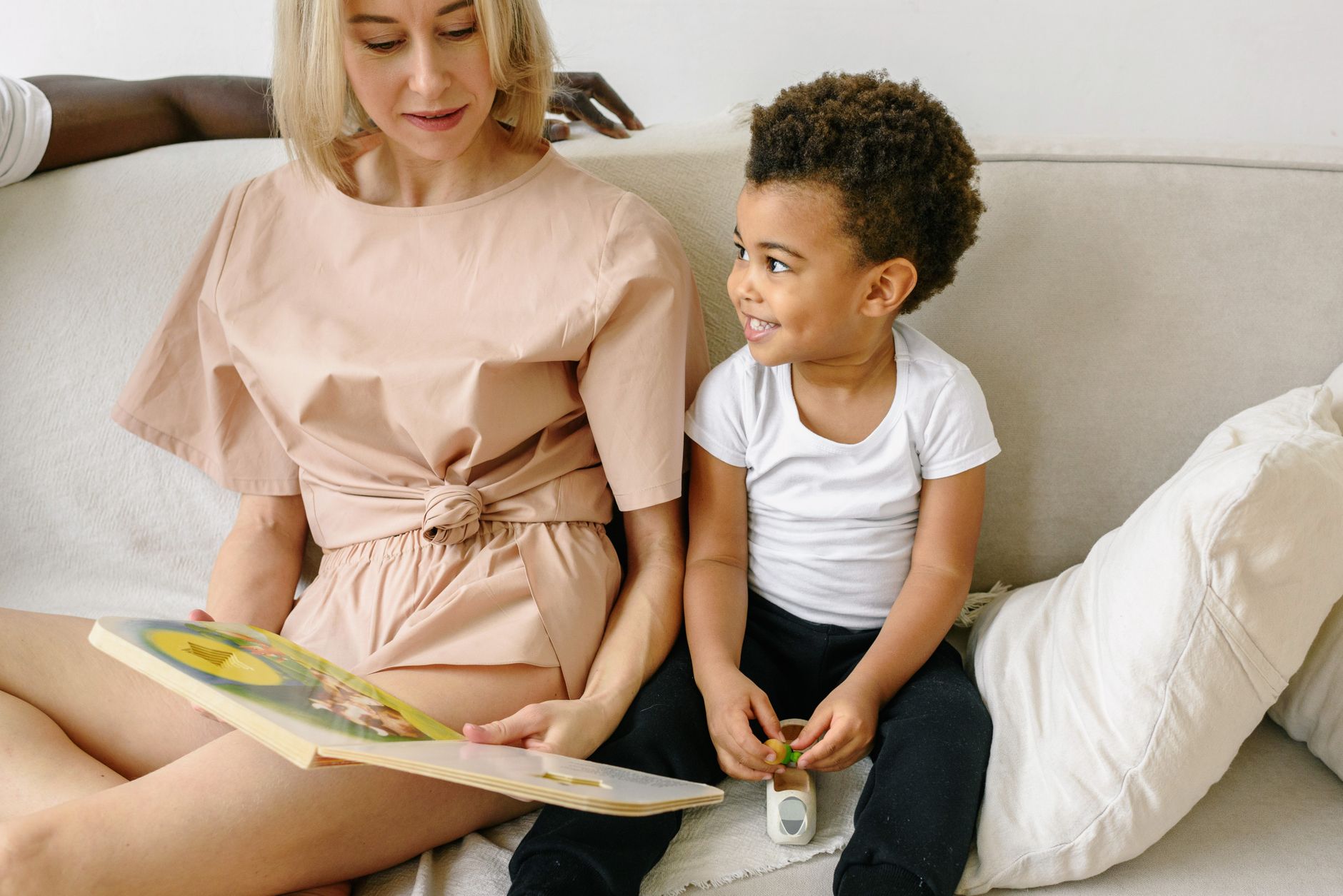 A mom sitting on the floor with her child, reading a book.