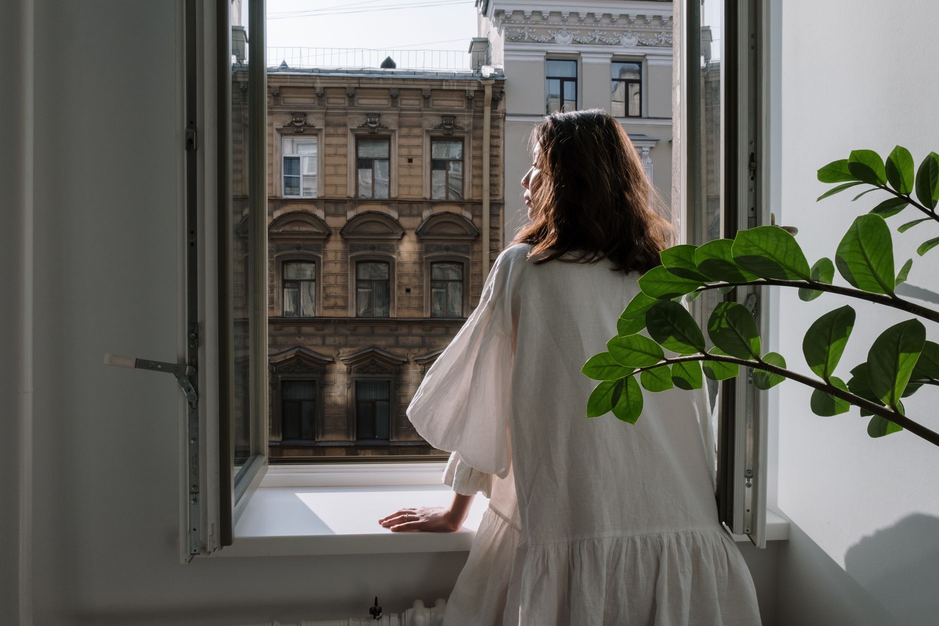 A thoughtful pregnant woman looking out a window.