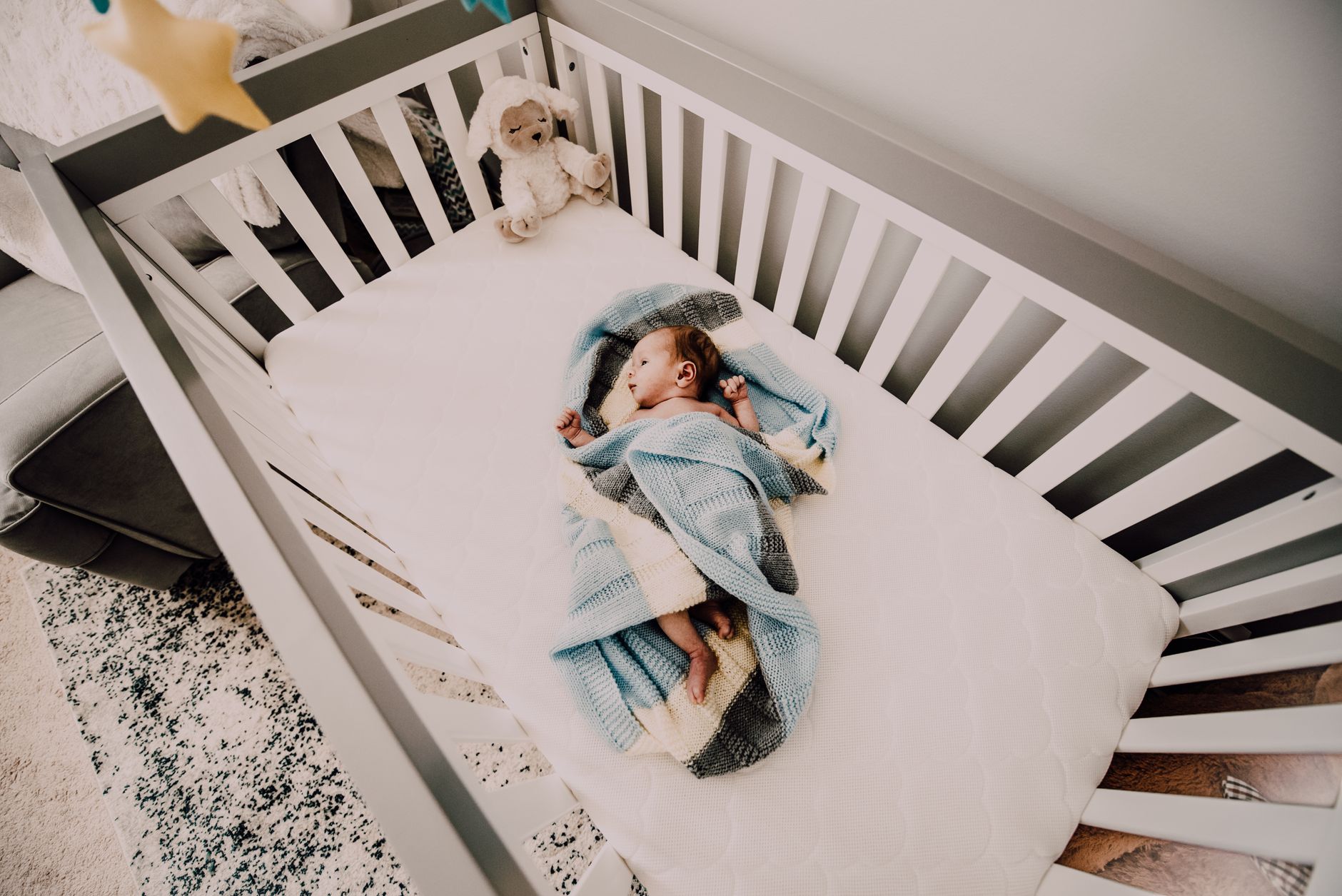 A baby sleeping soundly on their back in a portable travel crib, demonstrating safe sleep practices while away from home.