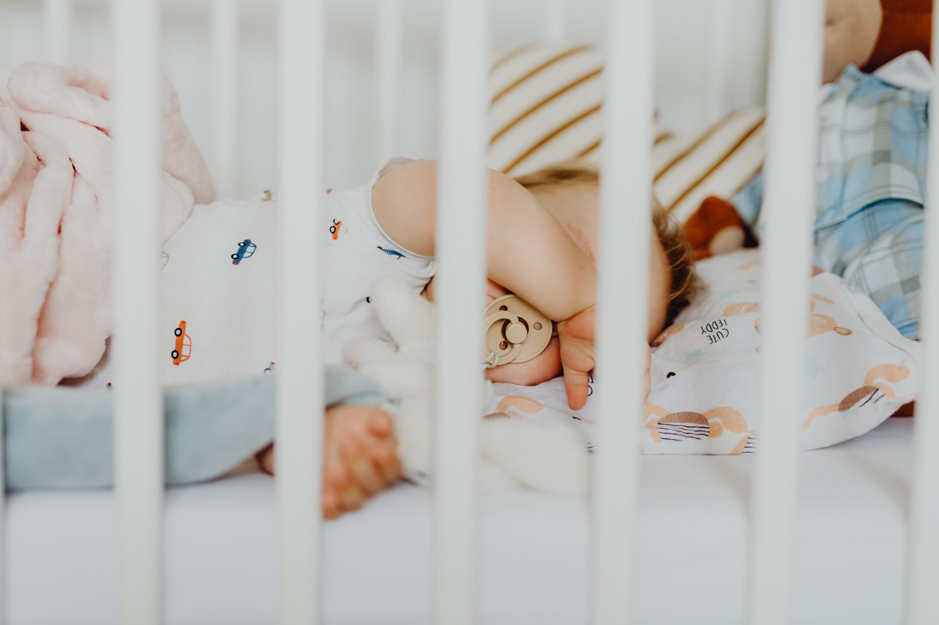 A peaceful baby sleeping on their back in a crib, with a pacifier gently in their mouth, illustrating safe sleep practices.