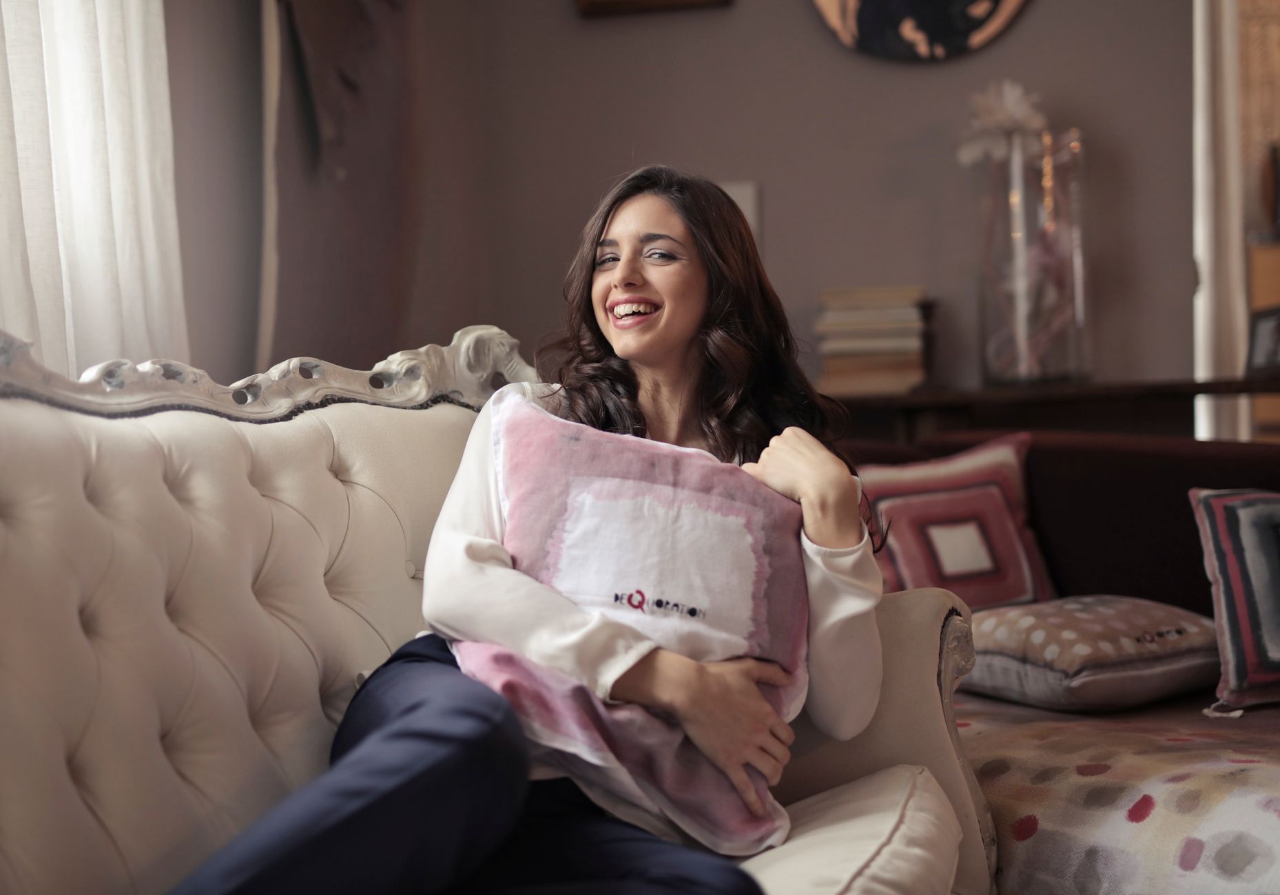 Pregnant woman applying a warm compress to her upper back while seated on a comfy couch, soft natural lighting