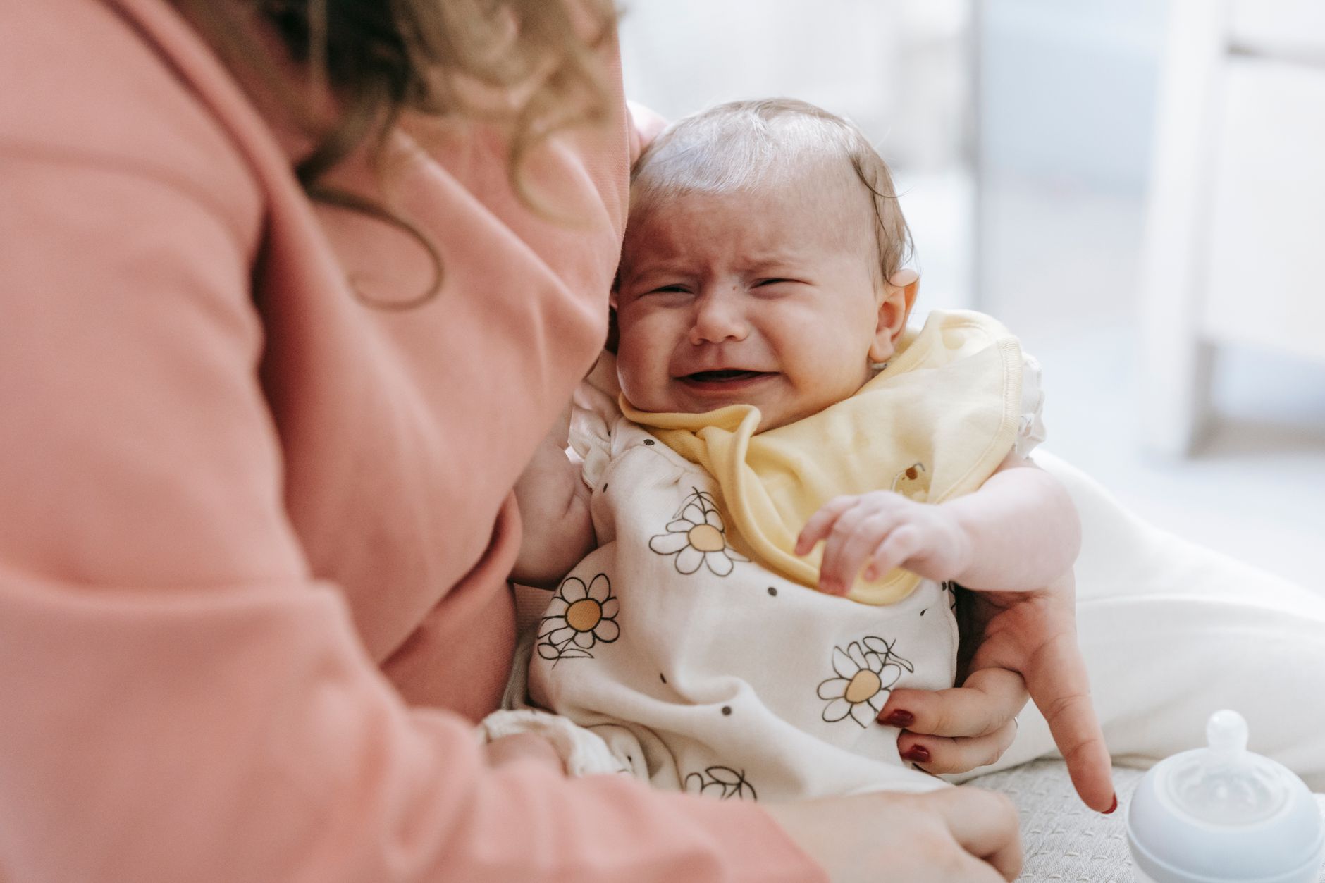 A concerned parent holding their baby, gently patting their back, suggesting comfort for digestive issues or fussiness