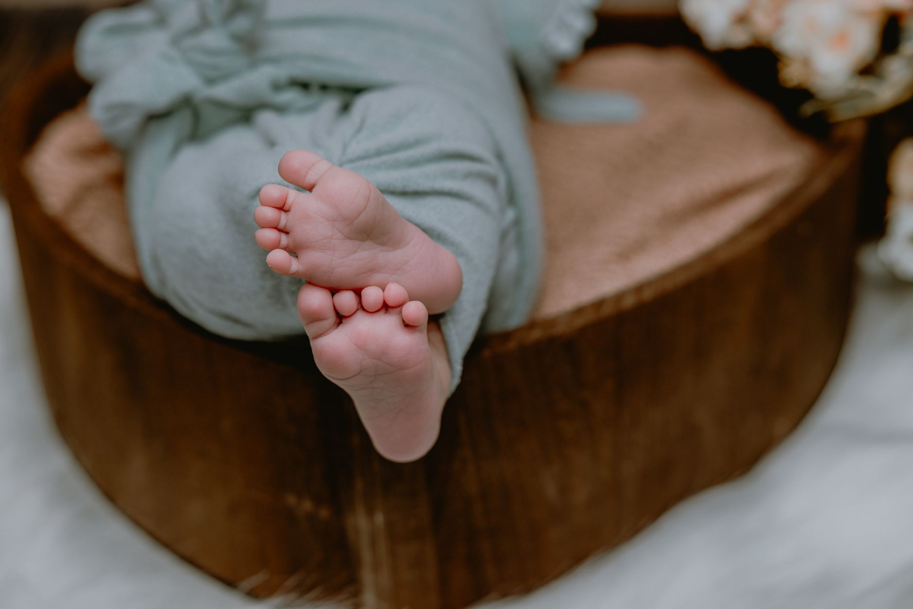 Warm blanket covering a newborn’s foot while a pulse‑oximeter sensor is attached, showing clear display of oxygen saturation and heart rate
