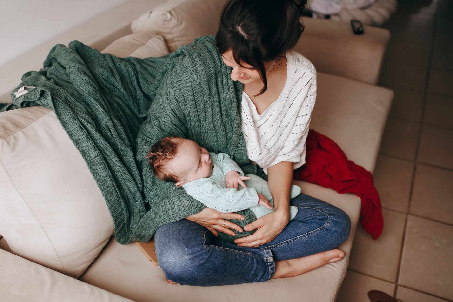 A stepchild gently holding a baby with an adult nearby, ensuring safety