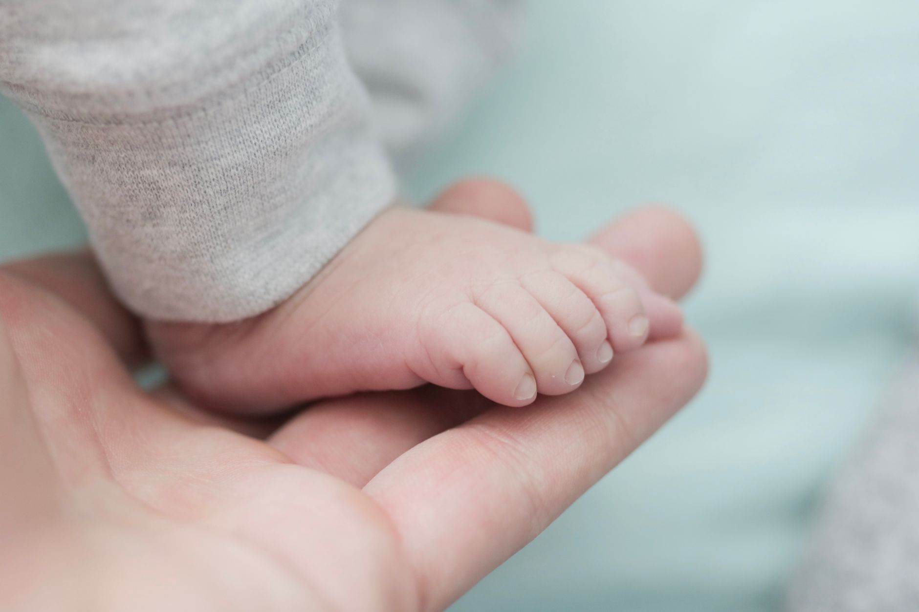 A mother's hand holding her newborn's foot, symbolizing protection and new life.