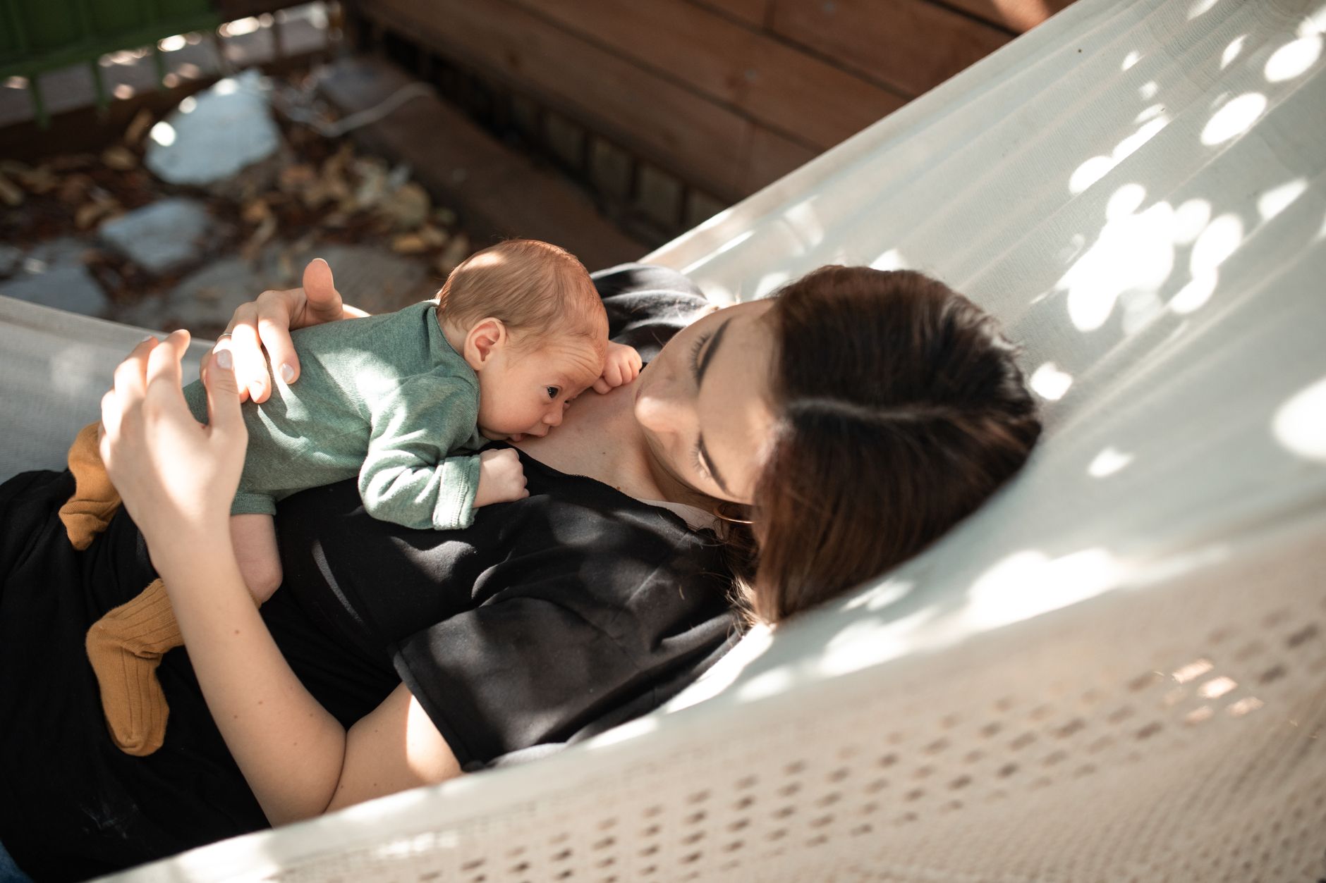 Mother holding a newborn and toddler, eyes closed, practicing mindfulness during tandem nursing