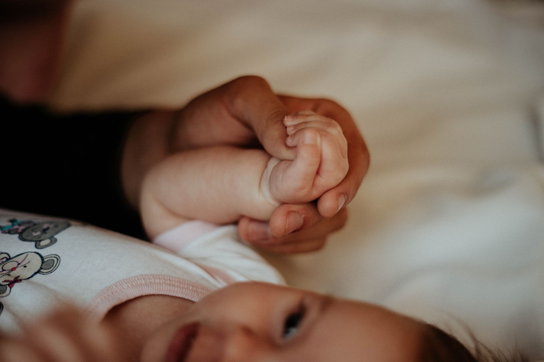 Hands of parents gently holding a newborn baby, symbolizing protection