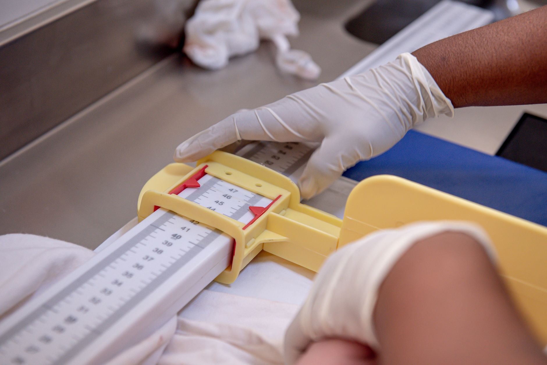 Close‑up of a neonatal mask being positioned on a newborn mannequin, showing proper seal and hand placement