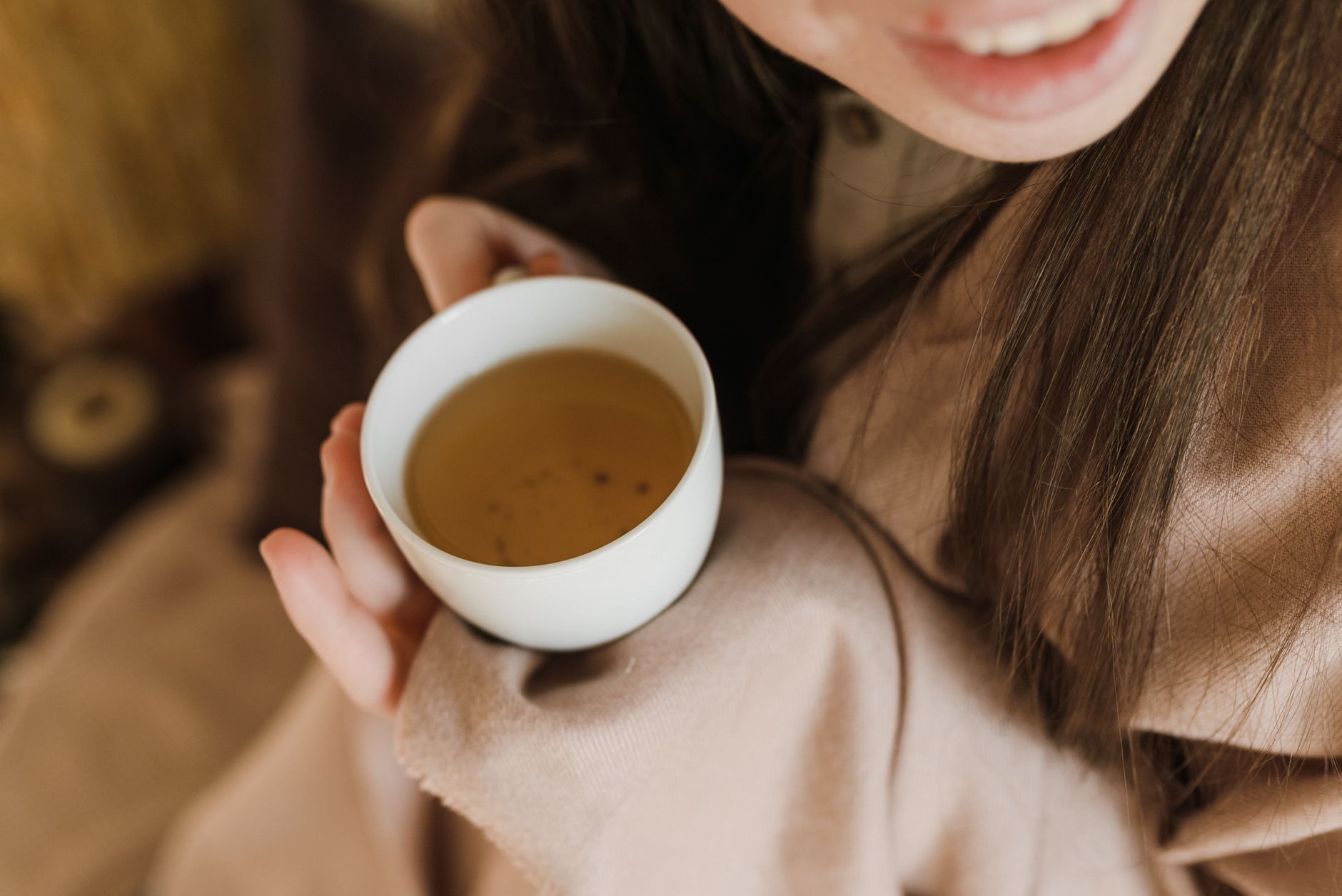 A pregnant woman resting on a couch, gently placing her hand on her growing belly, with a soft blanket and a cup of herbal tea nearby