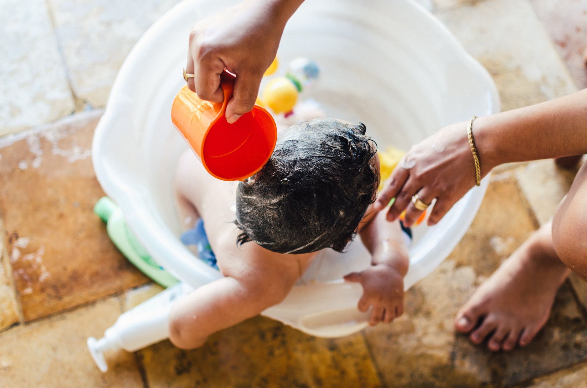 Toddler helping with baby bath