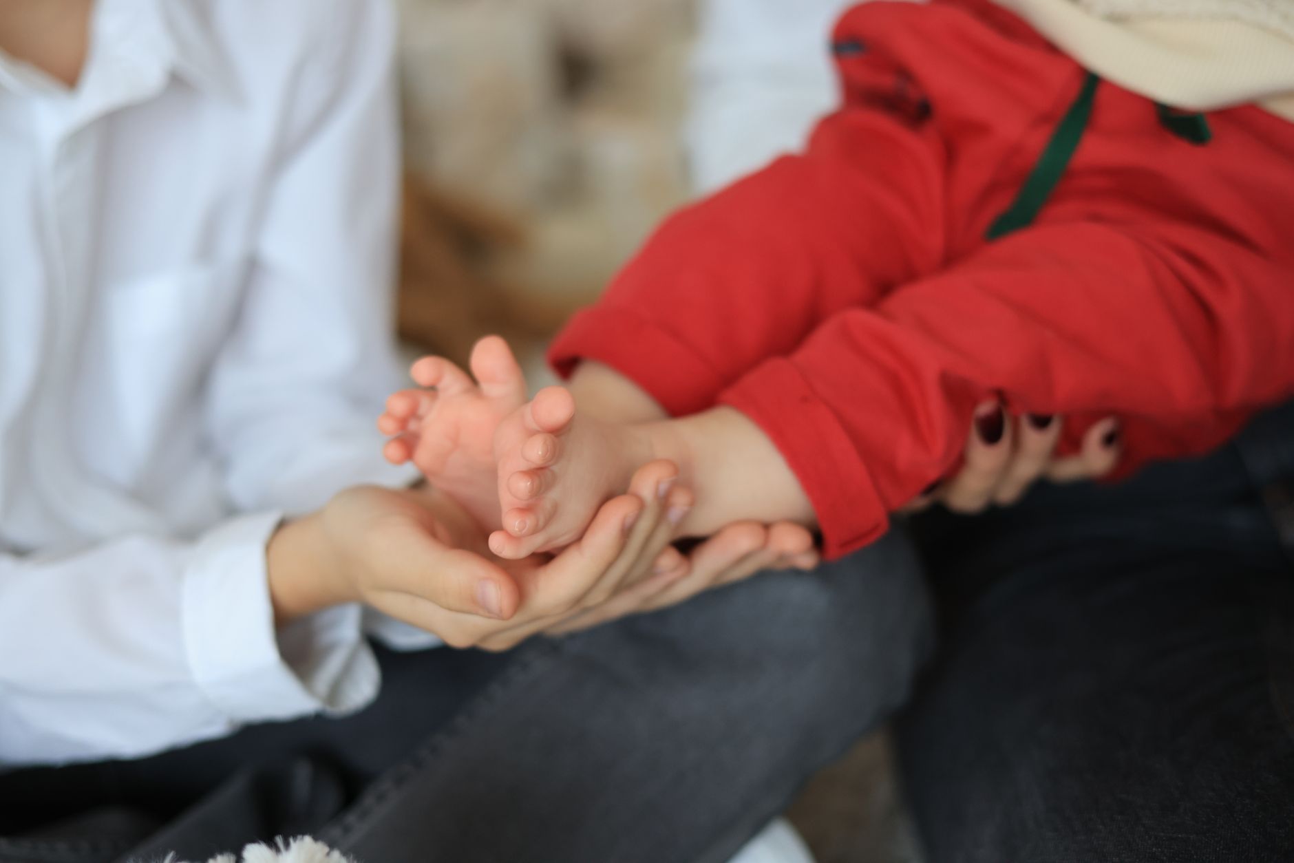 Toddler gently touching newborn’s hand