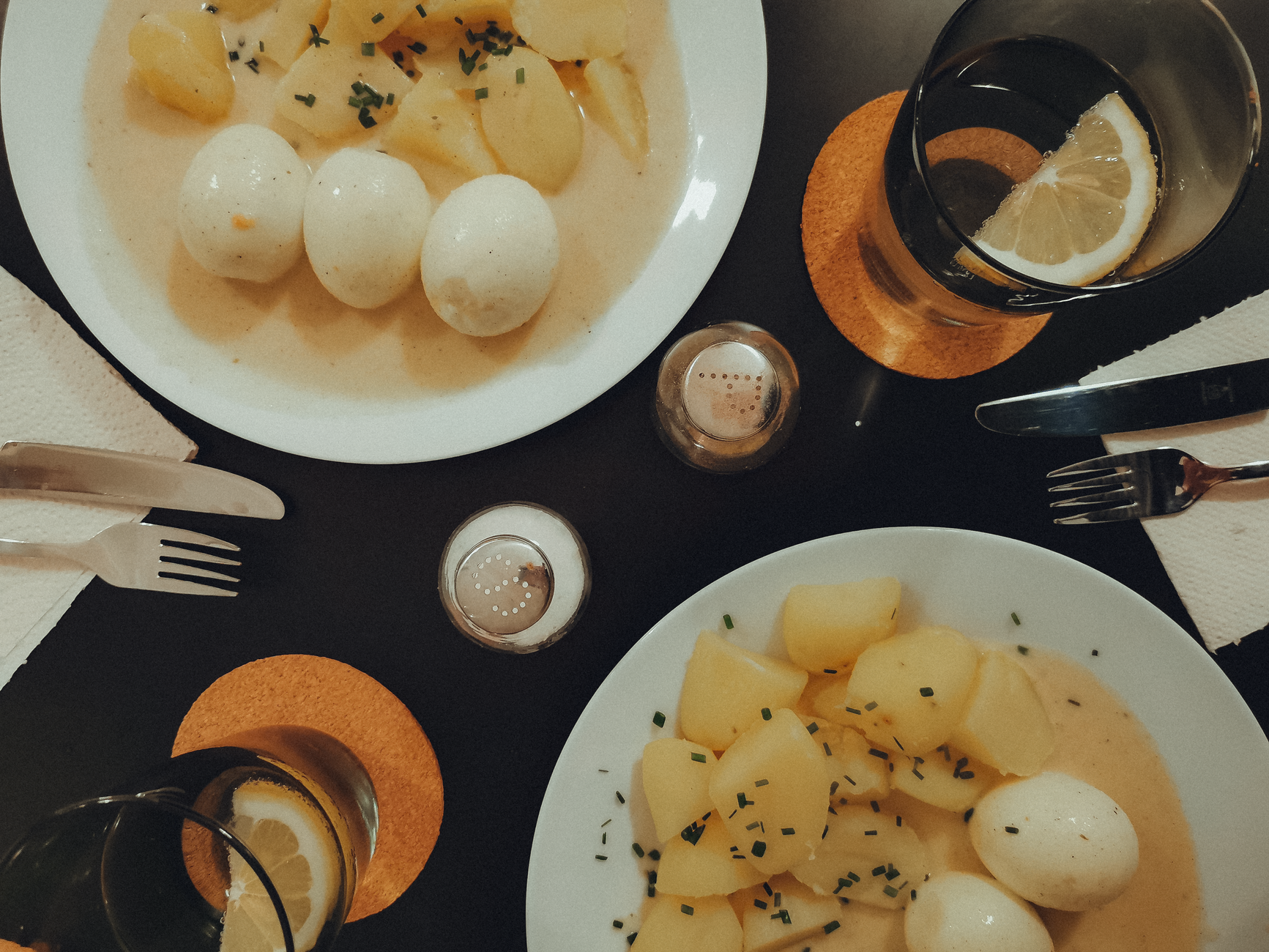 A pastel baby bowl containing a smooth peanut‑banana mash, a tiny egg‑veggie frittata, and a pink fish‑sweet potato puree, photographed with soft natural light and a wooden backdrop