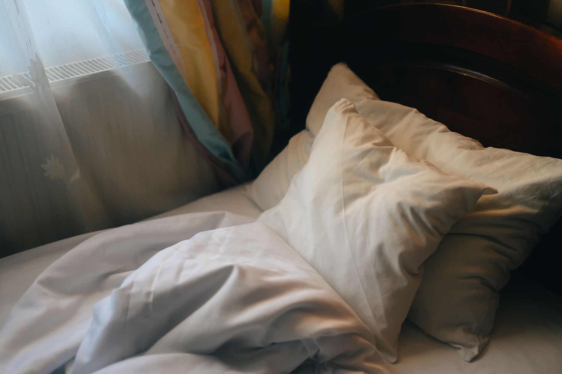 A soft, angled wedge pillow propped behind a pregnant woman's shoulders, with a cozy blanket and a nightstand lamp creating a warm bedtime scene