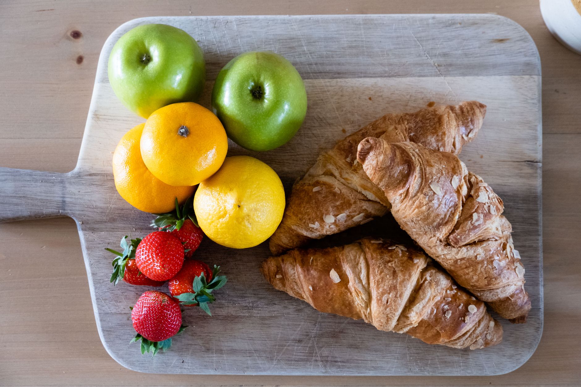 Fresh fruit platter with citrus, berries, and a glass of fortified soy milk on a wooden table, bright natural light