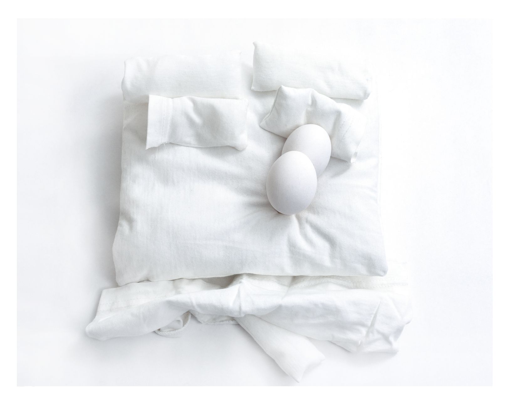 Various pregnancy pillows (U-shaped, C-shaped, wedge) neatly arranged on a bed, showcasing different sizes and shapes, with clean white bedding.