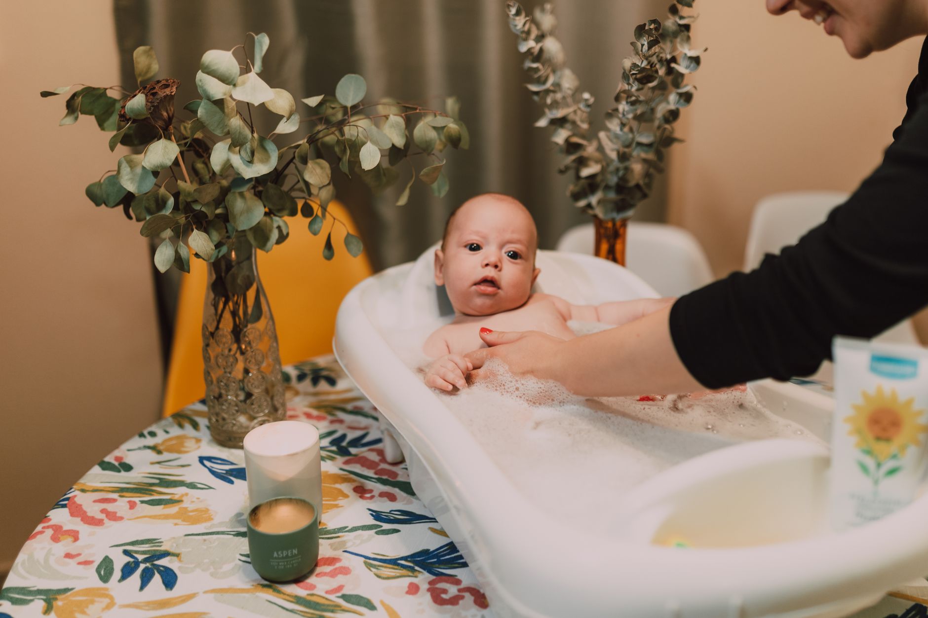 Gentle hands giving a newborn a sponge bath, carefully avoiding the umbilical cord area, warm and calm atmosphere