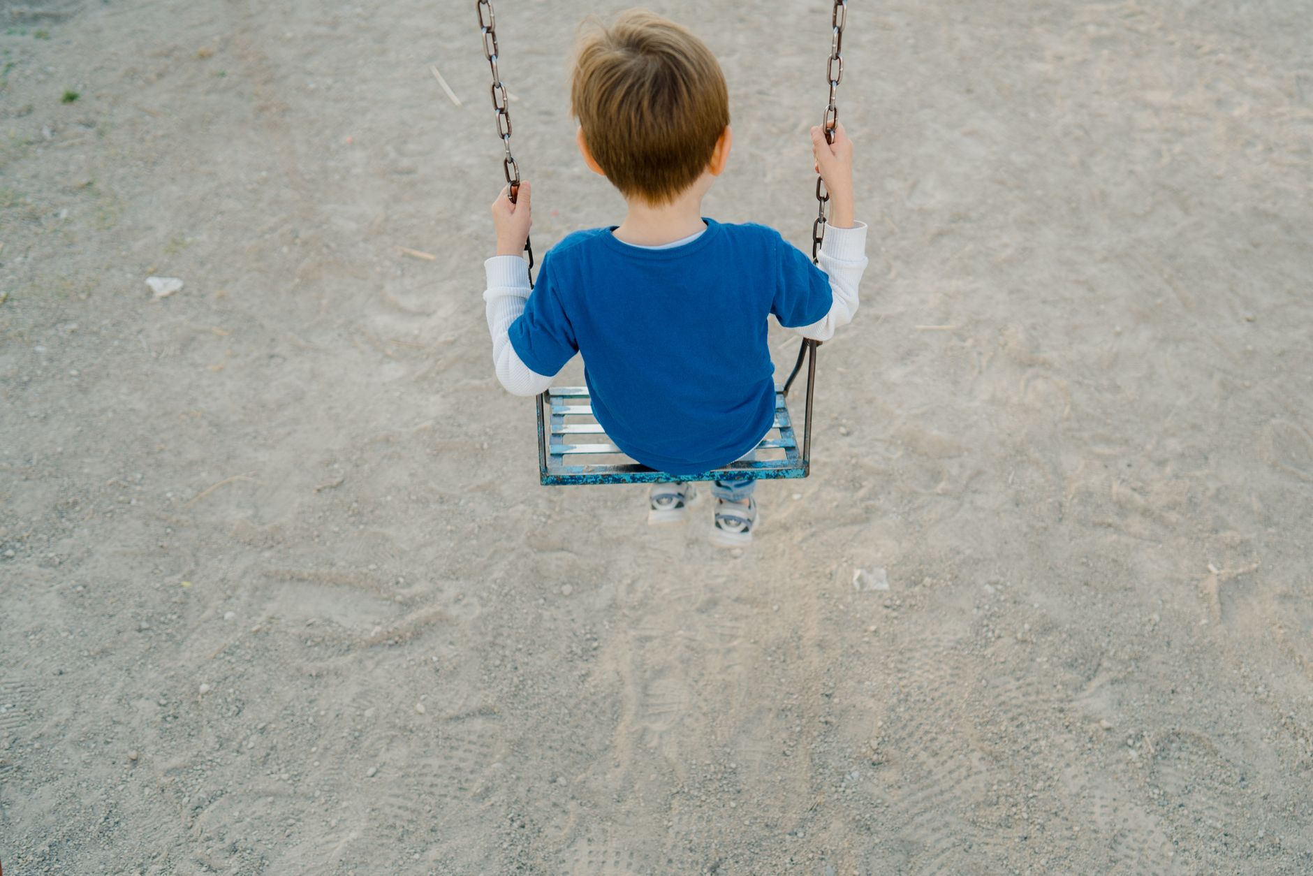 A young child sitting on a swing in a playground, looking up and smiling, symbolizing the 'playground test' for a baby name