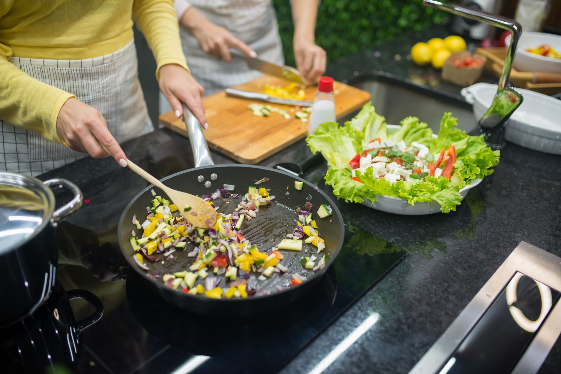 A pregnant woman in a light‑filled kitchen preparing a low‑fat vegetable stir‑fry, showing a wholesome, pregnancy‑friendly meal