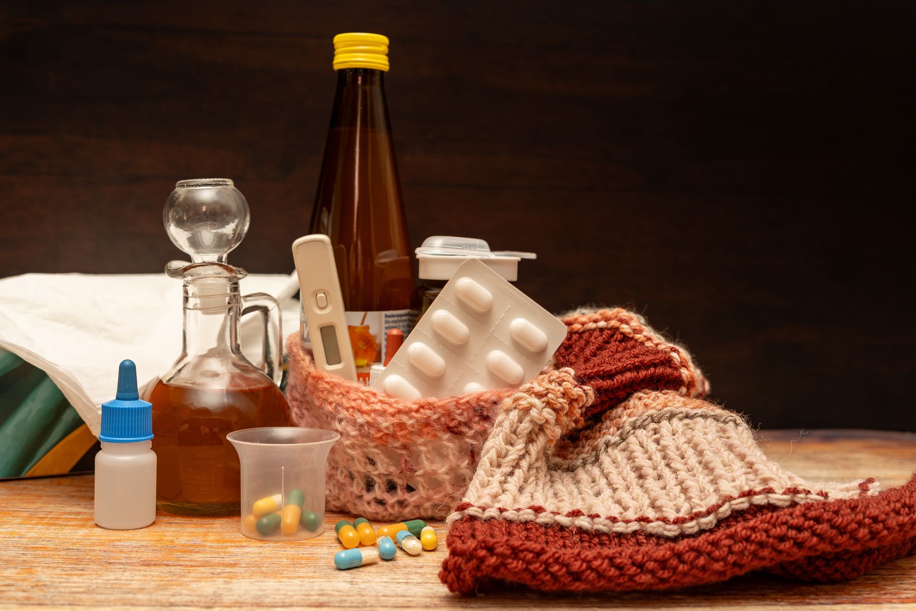 A variety of pregnancy-safe cold and flu remedies laid out on a clean counter, including a saline nasal spray, a Neti pot with sterile water, a jar of honey, a lemon, a humidifier, and a box of acetaminophen