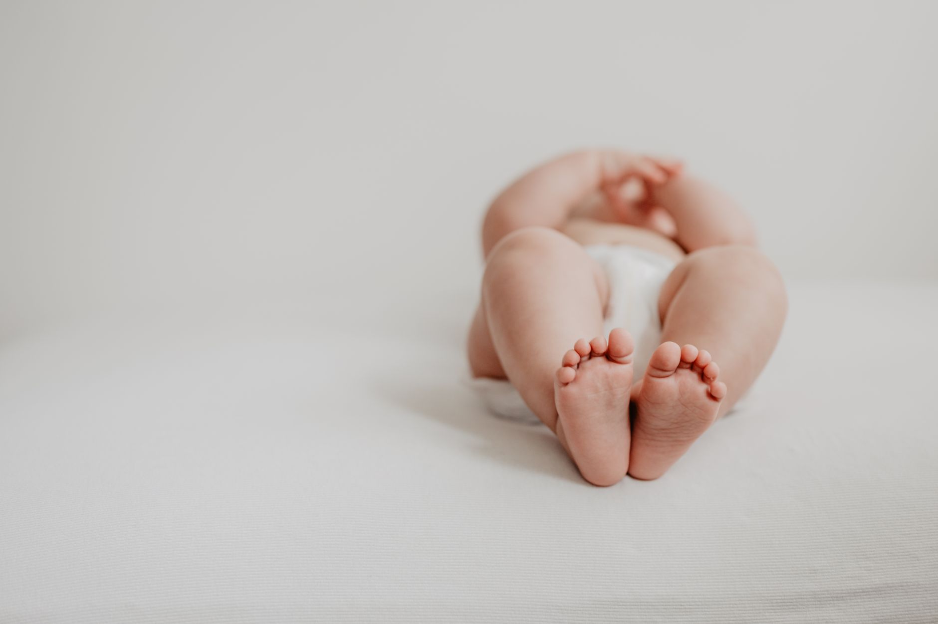 A smiling baby lying on a soft blanket with a fresh diaper, a gentle morning light highlighting the diaper’s snug fit