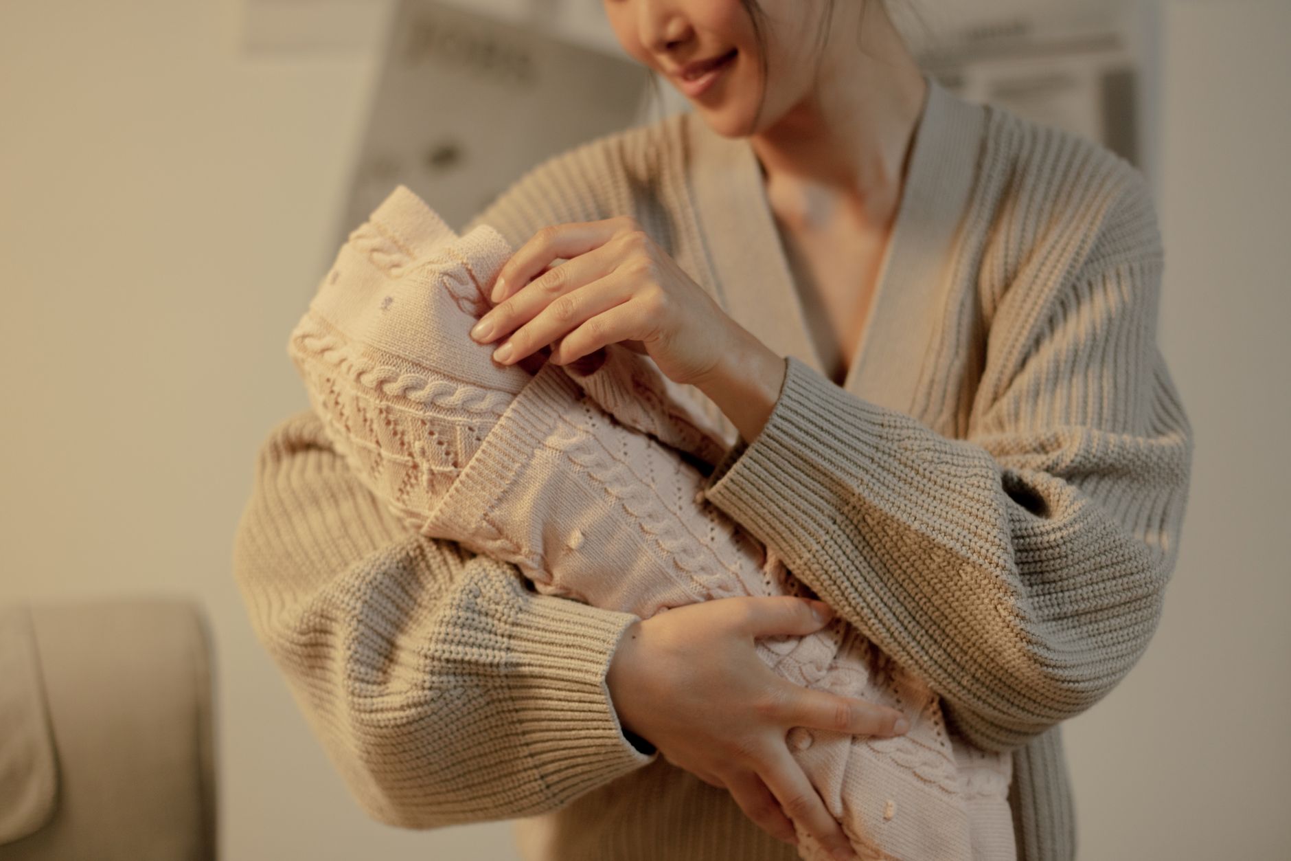A mother holding her newborn in a hospital nursery, soft natural light highlighting the baby’s pink skin and gentle smile