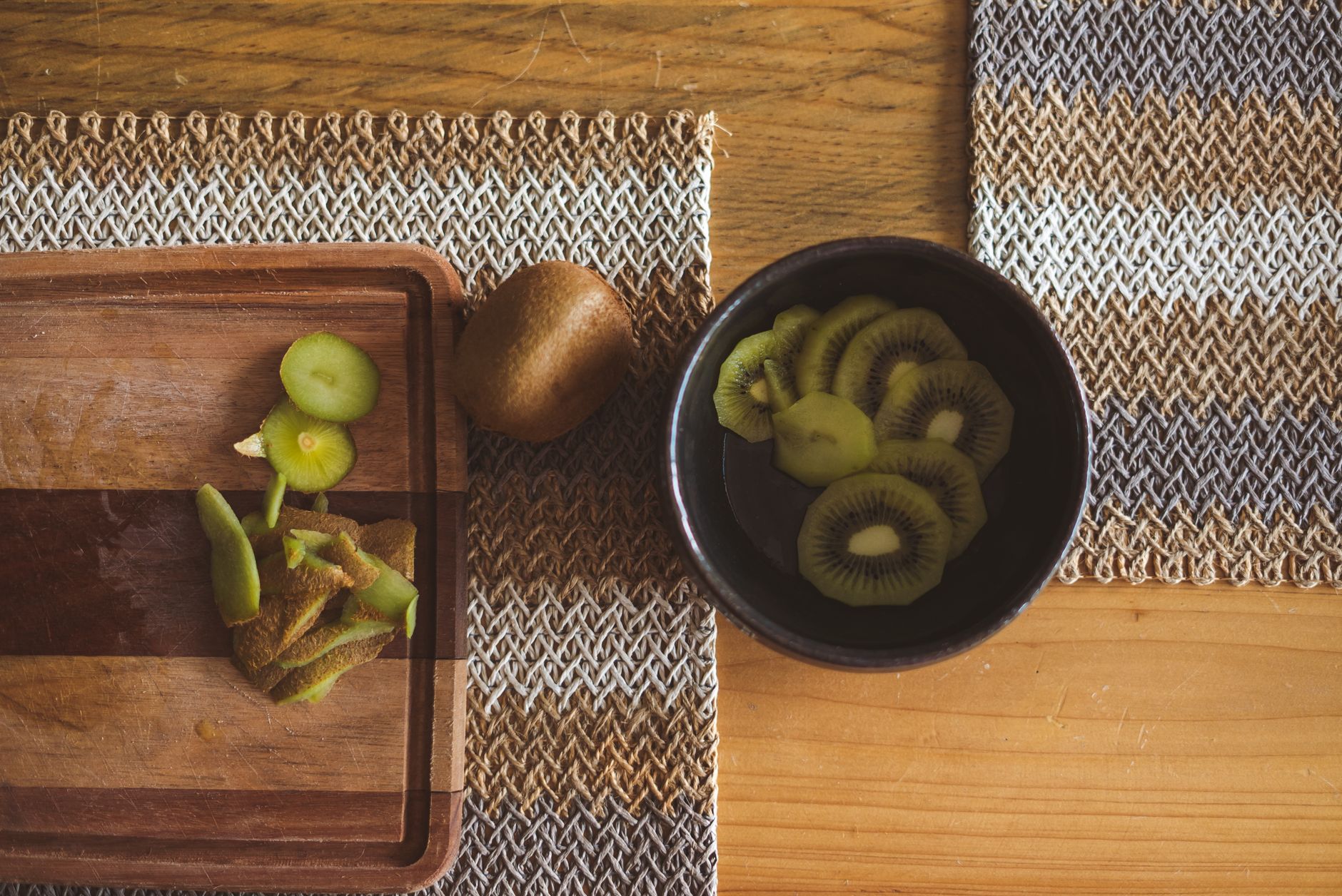 A colorful bowl of mixed berries, sliced kiwi, and nuts on a wooden table, bright natural light, photorealistic