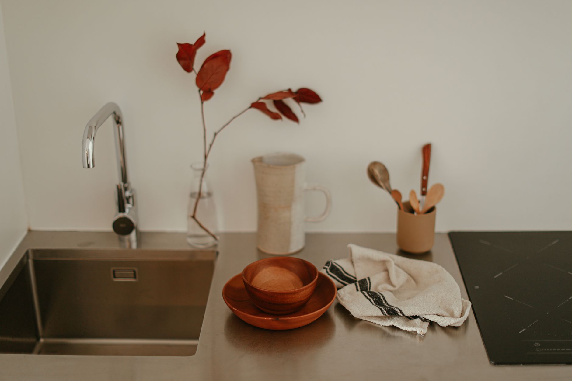 A glass of prune juice beside a bowl of fresh prunes, a measuring spoon of psyllium, and a water bottle, illustrating natural constipation remedies for pregnant individuals