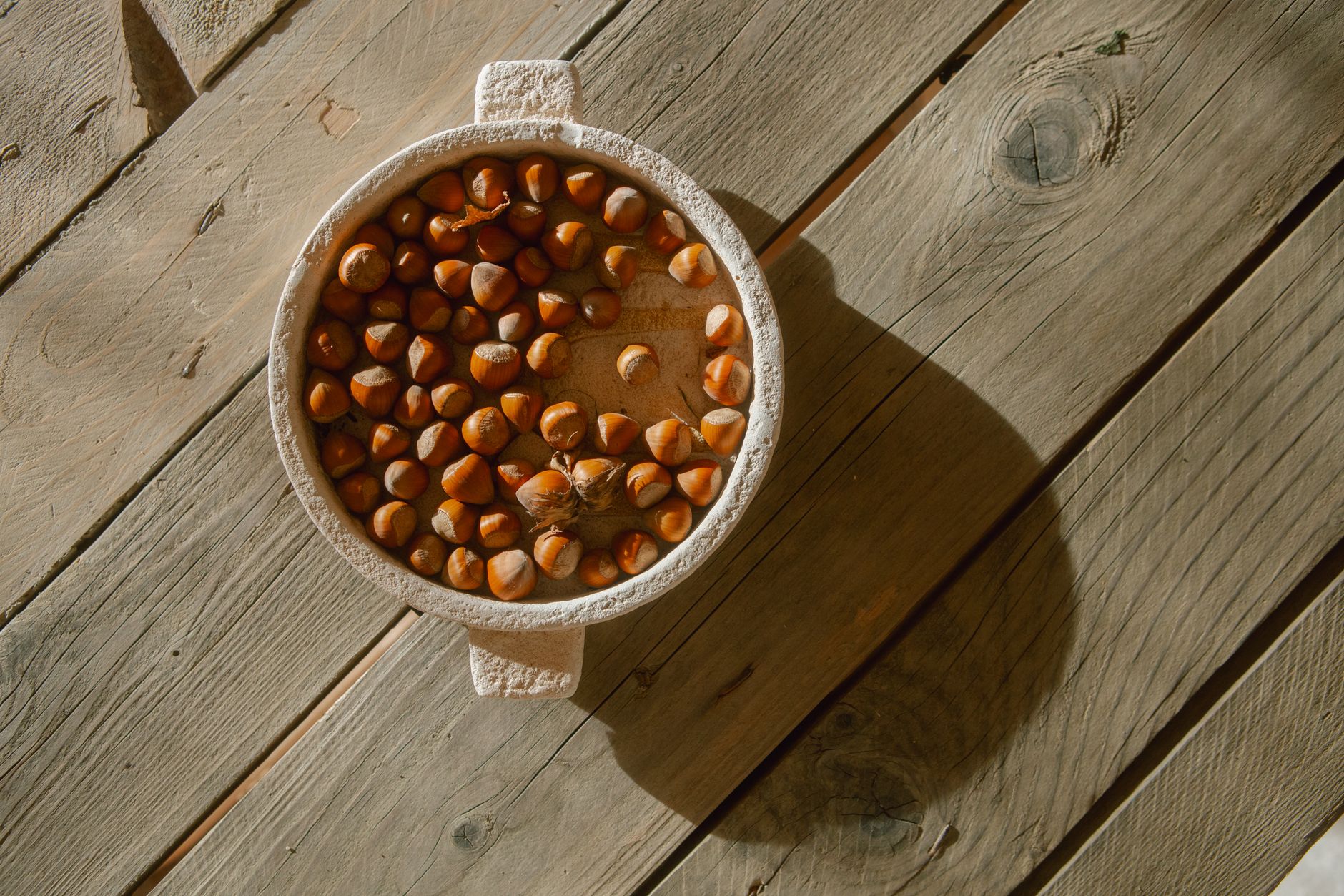 A soft‑colored wooden board displaying a bowl of warm oatmeal, a small cup of water, and a plush baby blanket, bright morning light highlighting the food