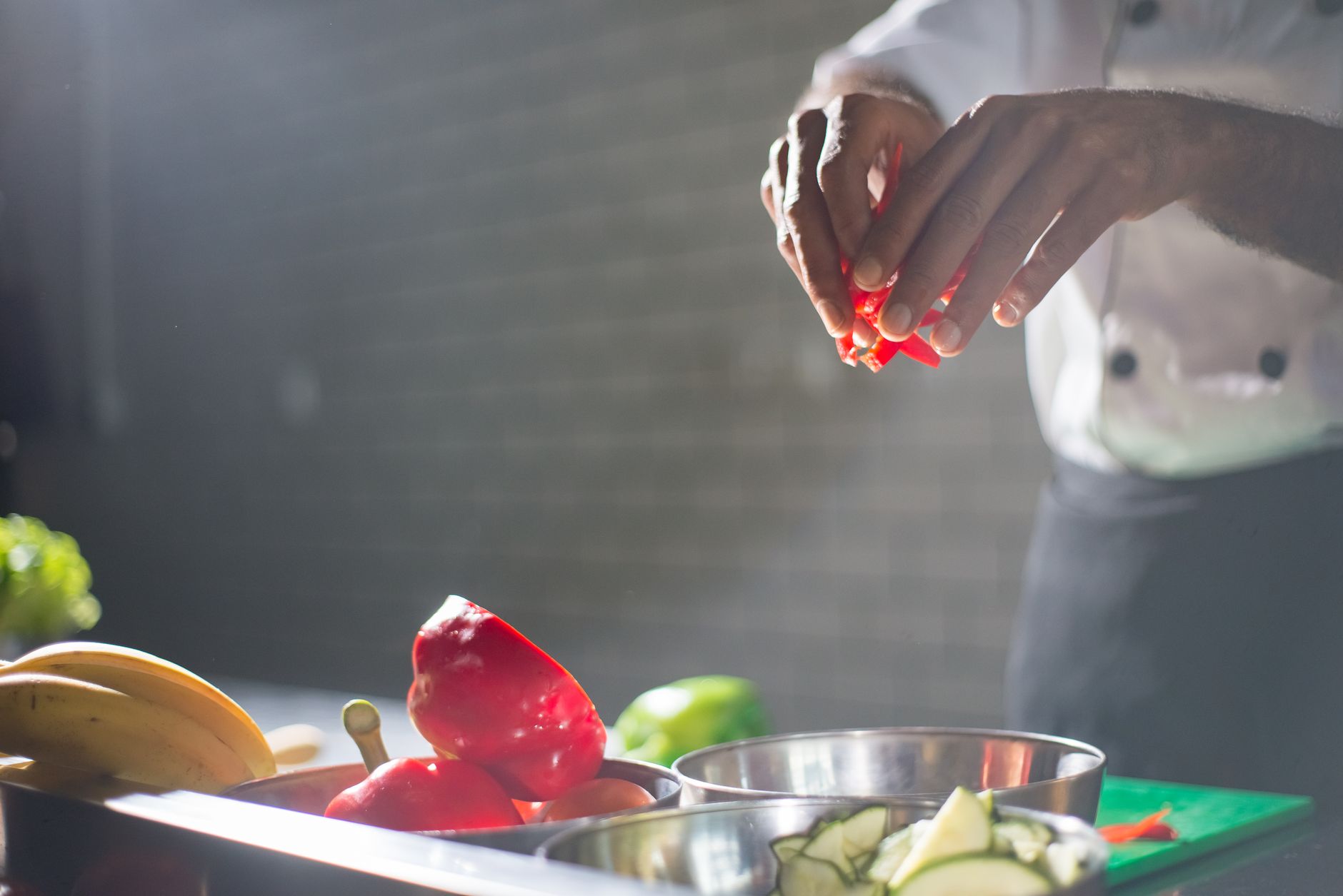 A close‑up of a hand holding a saline nasal spray bottle next to a small bowl of fresh ginger slices, bright kitchen lighting