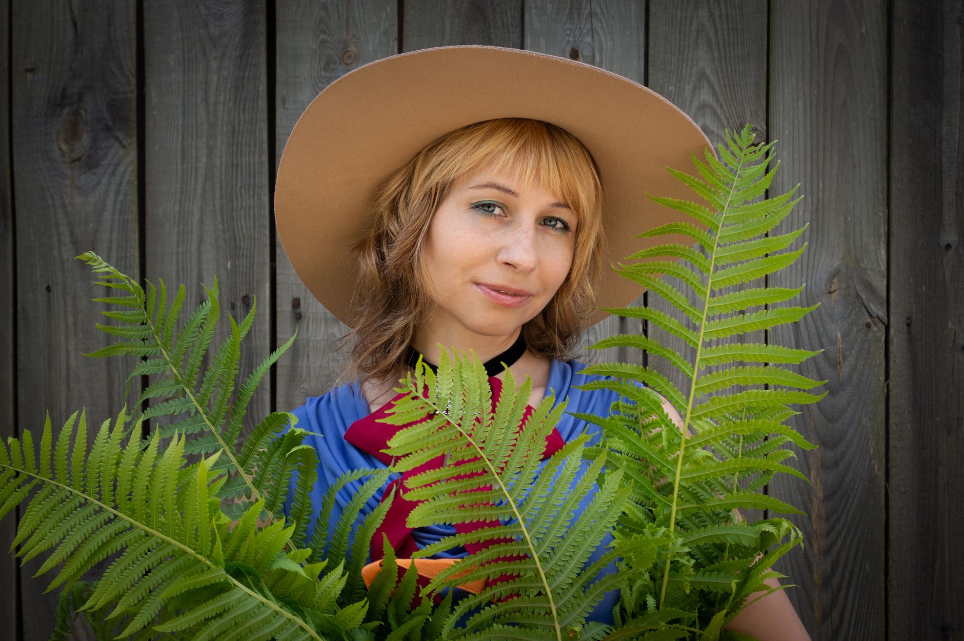 A sunny outdoor scene with a pregnant woman wearing a wide‑brim hat, UPF‑rated shirt, and holding a bottle of Blue Lizard Australian Sunscreen, demonstrating safe sun practices