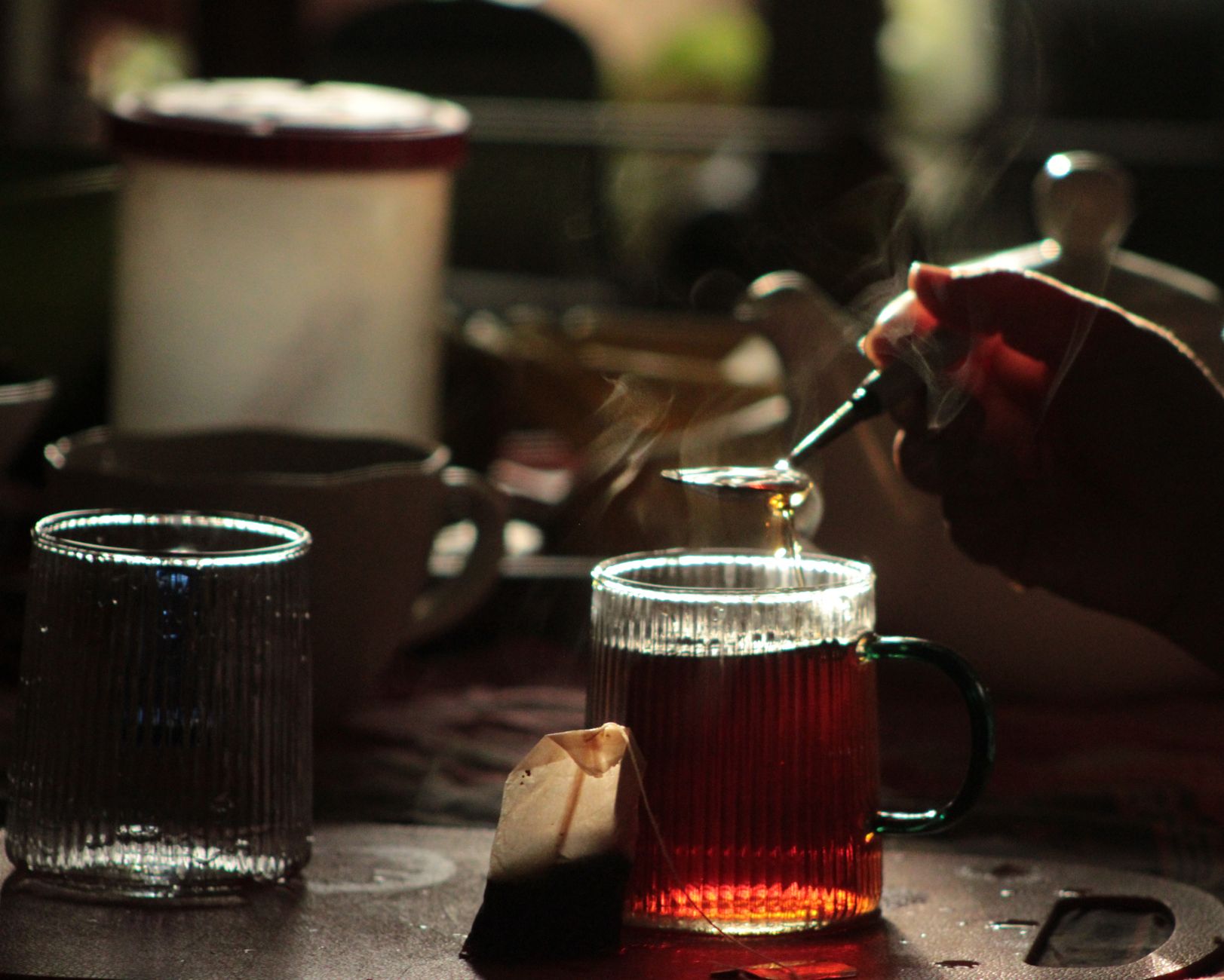 A steaming mug of herbal tea on a wooden table next to a handwritten note that says 'Stay hydrated' in soft pen, warm natural lighting highlighting the steam