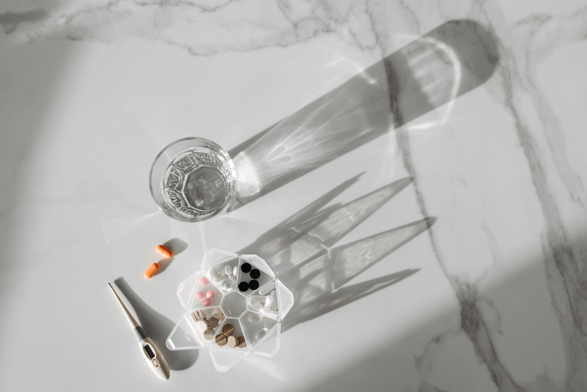 A soft, pastel kitchen counter with a glass of water, a bottle of infant formula, and a digital thermometer, bright natural light, inviting, clean aesthetic