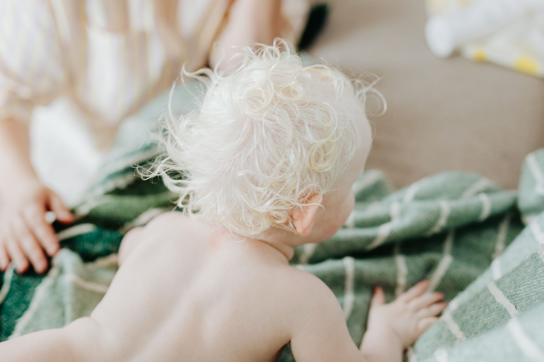 Close-up of a baby bathtub with a soft rubber ring, a gentle splash of warm water, and a pastel towel nearby