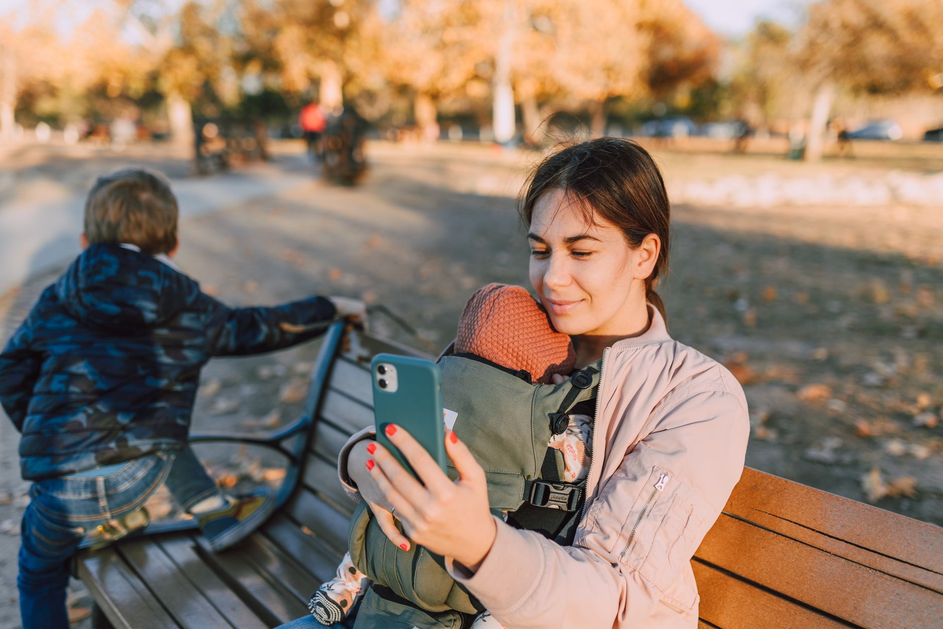 A mom holding her second baby while using a double baby carrier.
