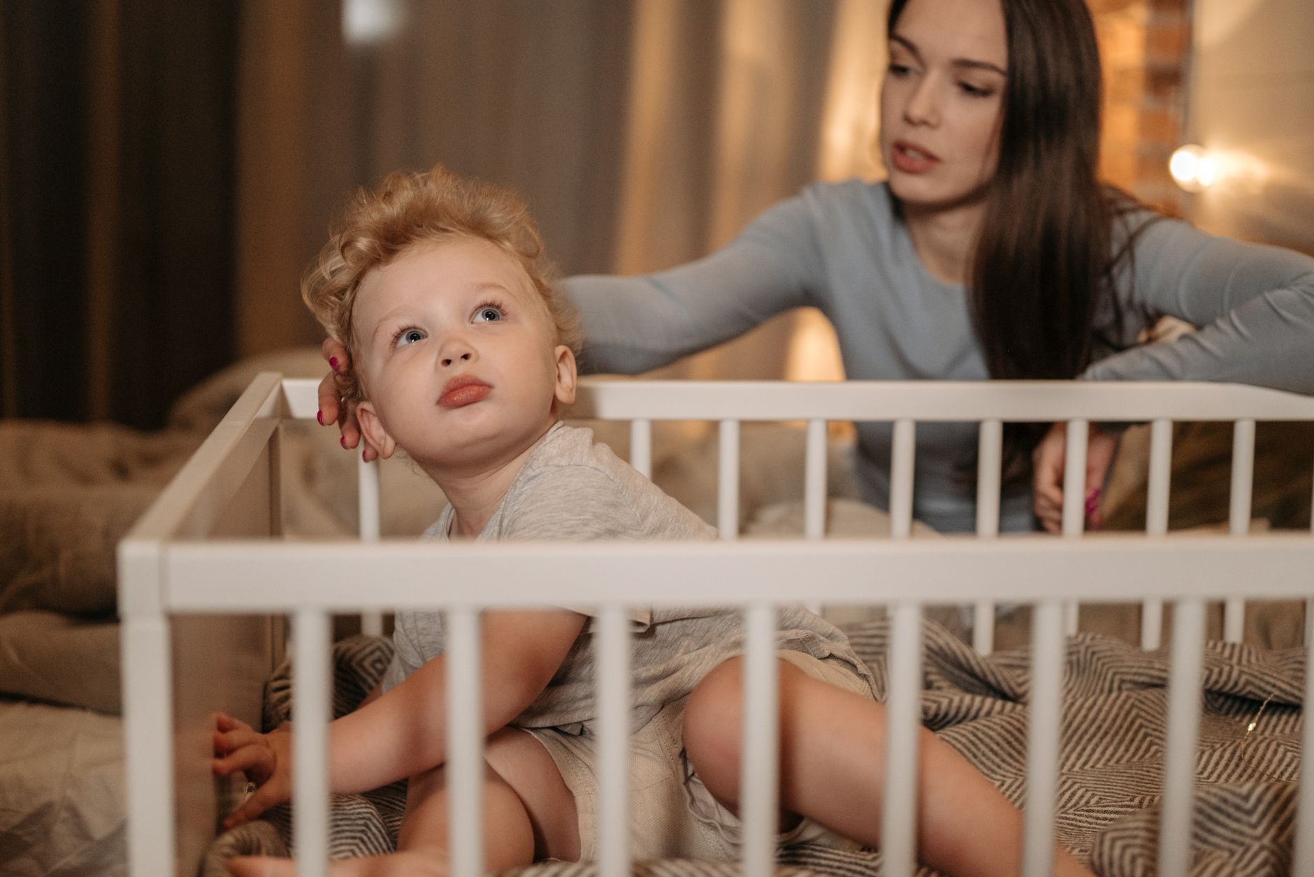 A parent's hands gently lowering a baby dressed in a sleep sack into a crib, illustrating a calm bedtime routine.