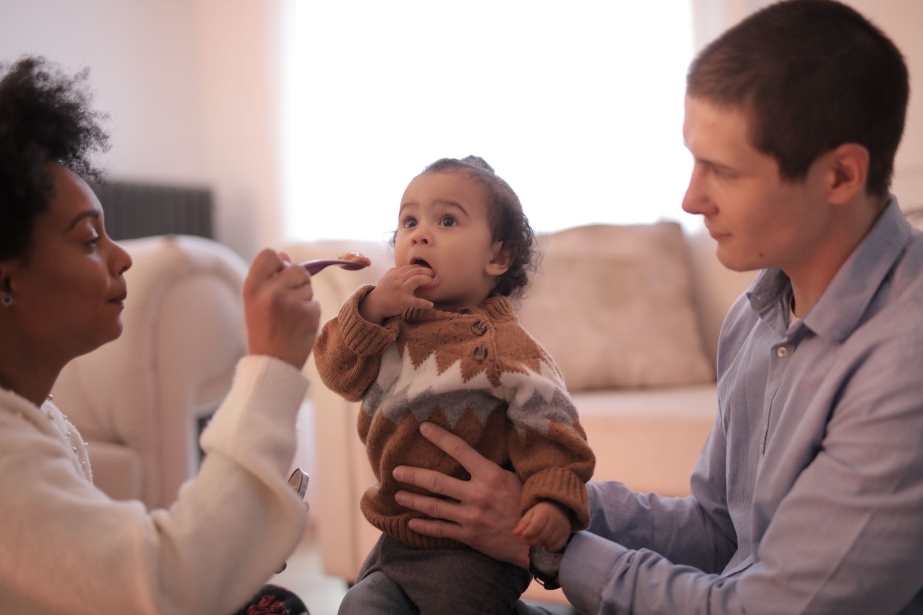 Parent supporting baby during spoon feeding