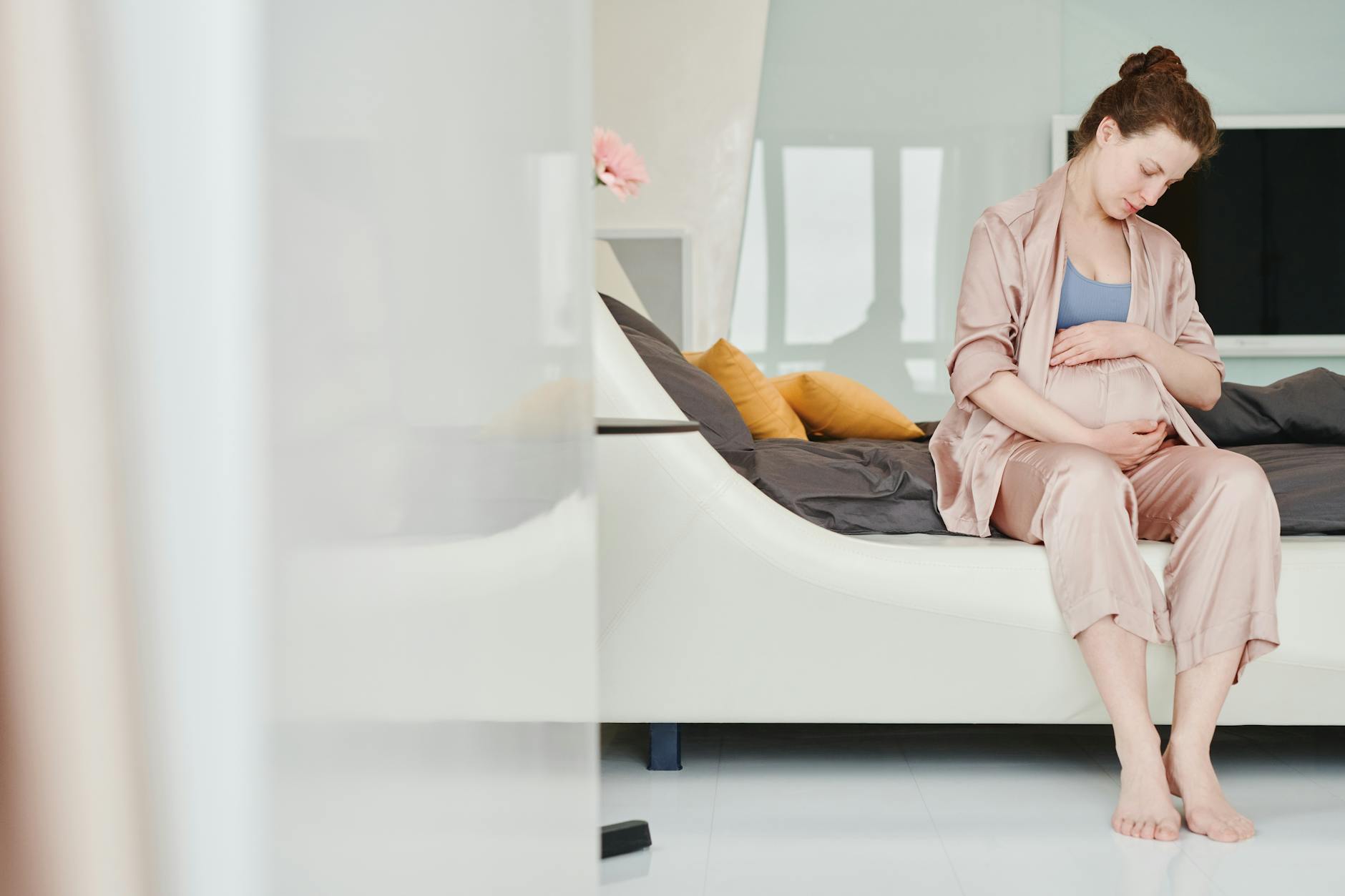 A pregnant woman looking concerned, holding her belly, with a blurred clock and a kick counter in the background suggesting time passing
