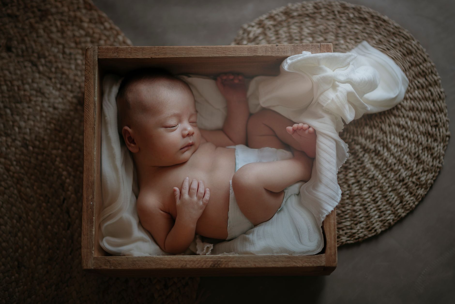 Soft‑focus photograph of a newborn swaddled in a blanket on a light‑colored wooden table, warm natural light, photorealistic