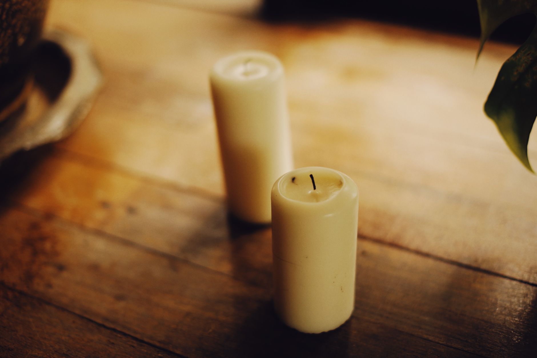 Soft focus photo of a glass of water beside a notebook and a gently lit candle, representing soothing self‑care during pregnancy
