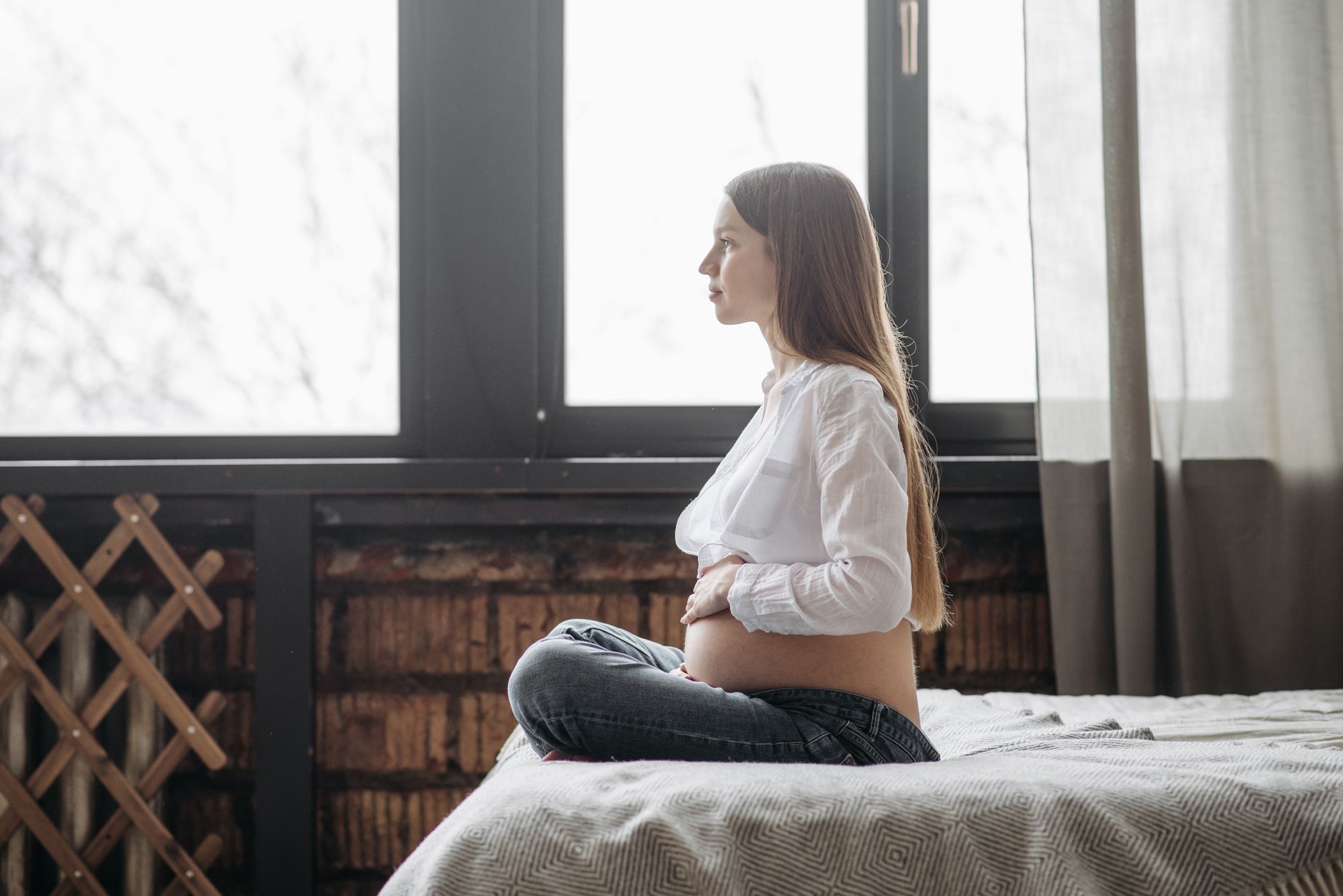 Pregnant woman performing a pelvic floor exercise while seated, soft natural light from a window, calm indoor setting, photorealistic