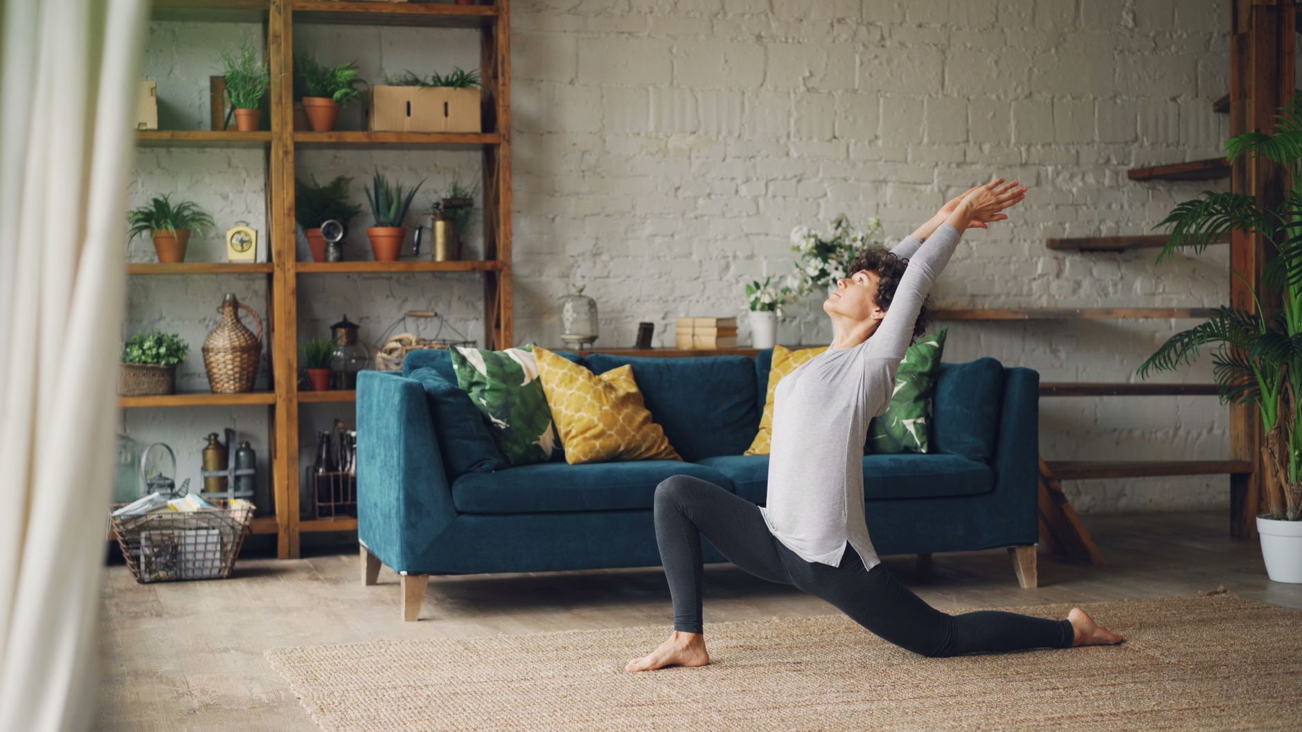 Pregnant woman practicing gentle yoga on a sunlit living room floor, soft cushions and a plant in the background, promoting relaxation and skin health